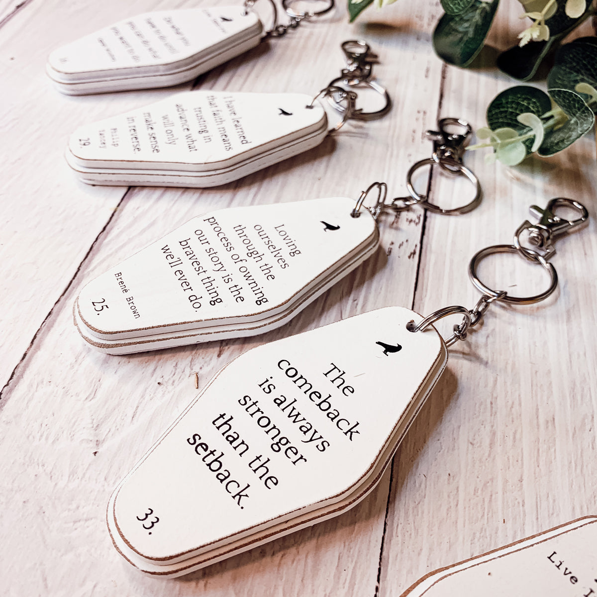 A collection of wooden key chains featuring various inspirational quotes, showcasing their durable design and stylish black and white colors.