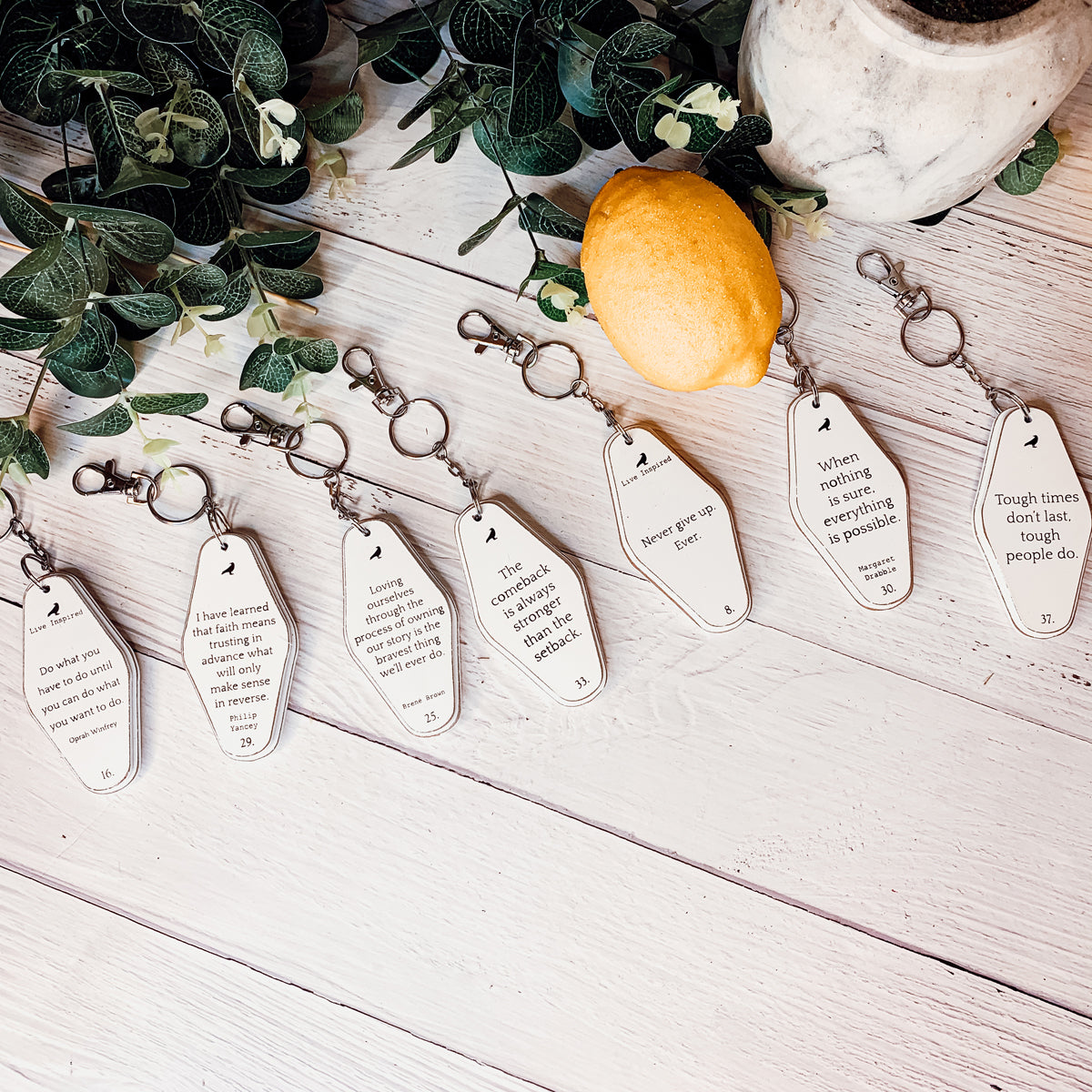 A collection of wooden key chains featuring various inspirational quotes, showcasing their durable design and stylish black and white colors.