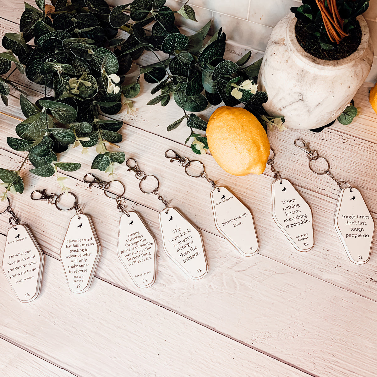 A collection of wooden key chains featuring various inspirational quotes, showcasing their durable design and stylish black and white colors.