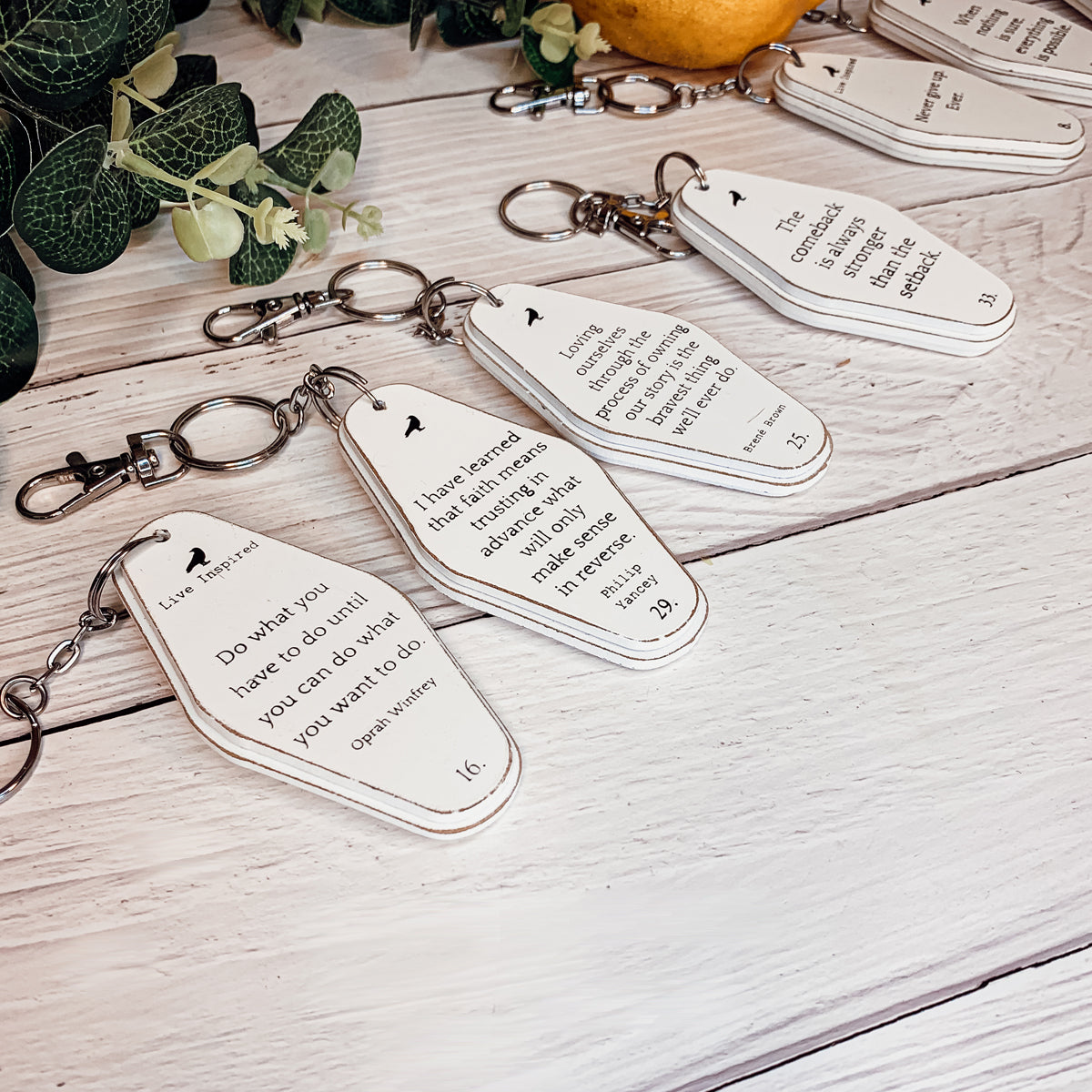 A collection of wooden key chains featuring various inspirational quotes, showcasing their durable design and stylish black and white colors.