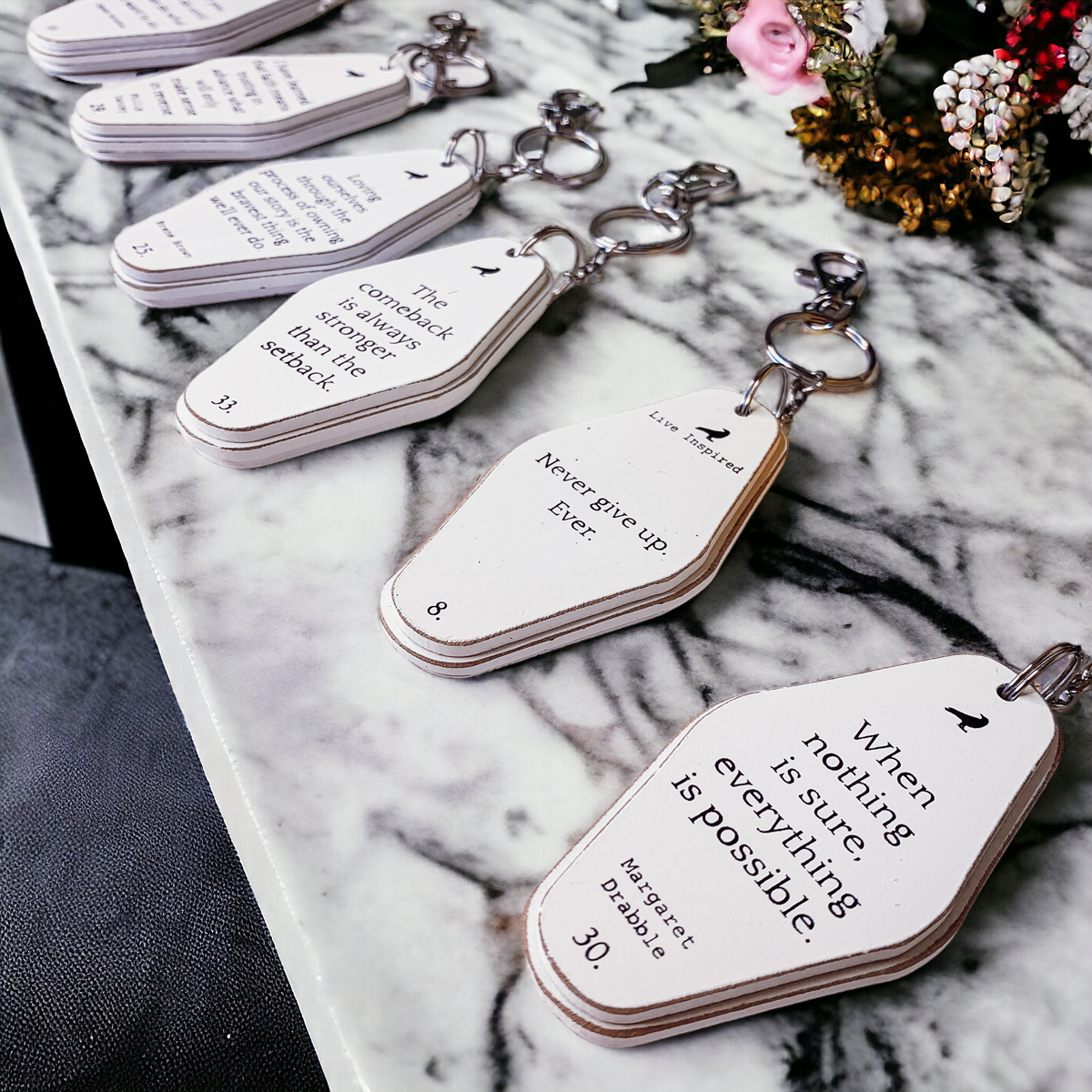 A collection of wooden key chains featuring various inspirational quotes, showcasing their durable design and stylish black and white colors.