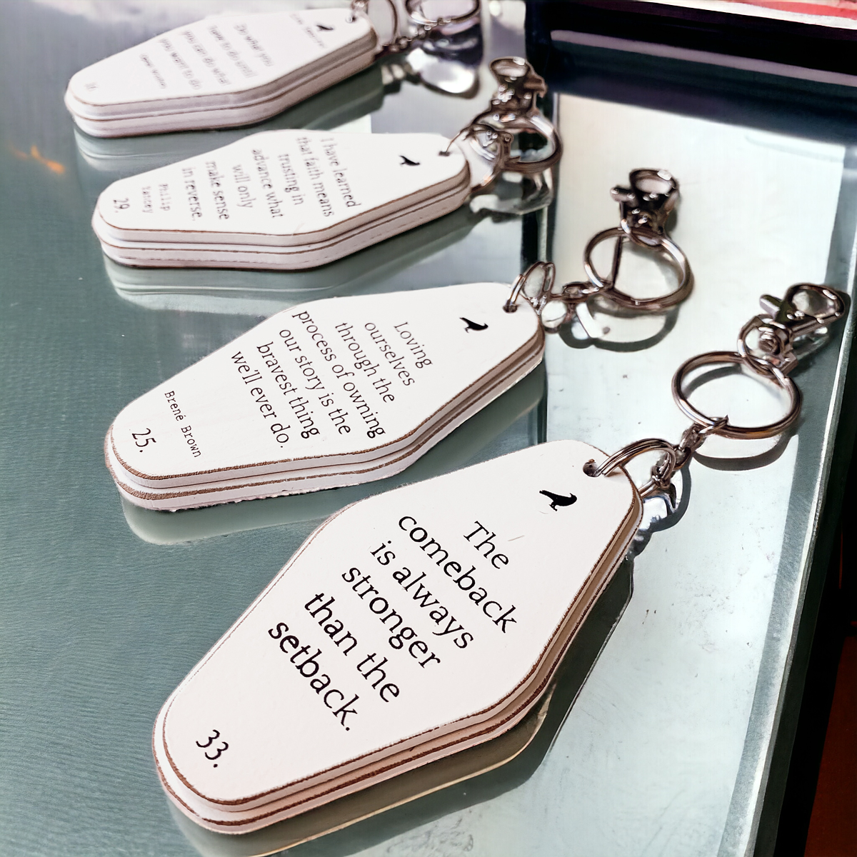 A collection of wooden key chains featuring various inspirational quotes, showcasing their durable design and stylish black and white colors.