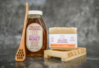 A beautifully arranged Self-Care Gift Set featuring Wildflower Honey with a dipper, All-Natural Honey Soap, and a wooden holder, perfect for pampering.