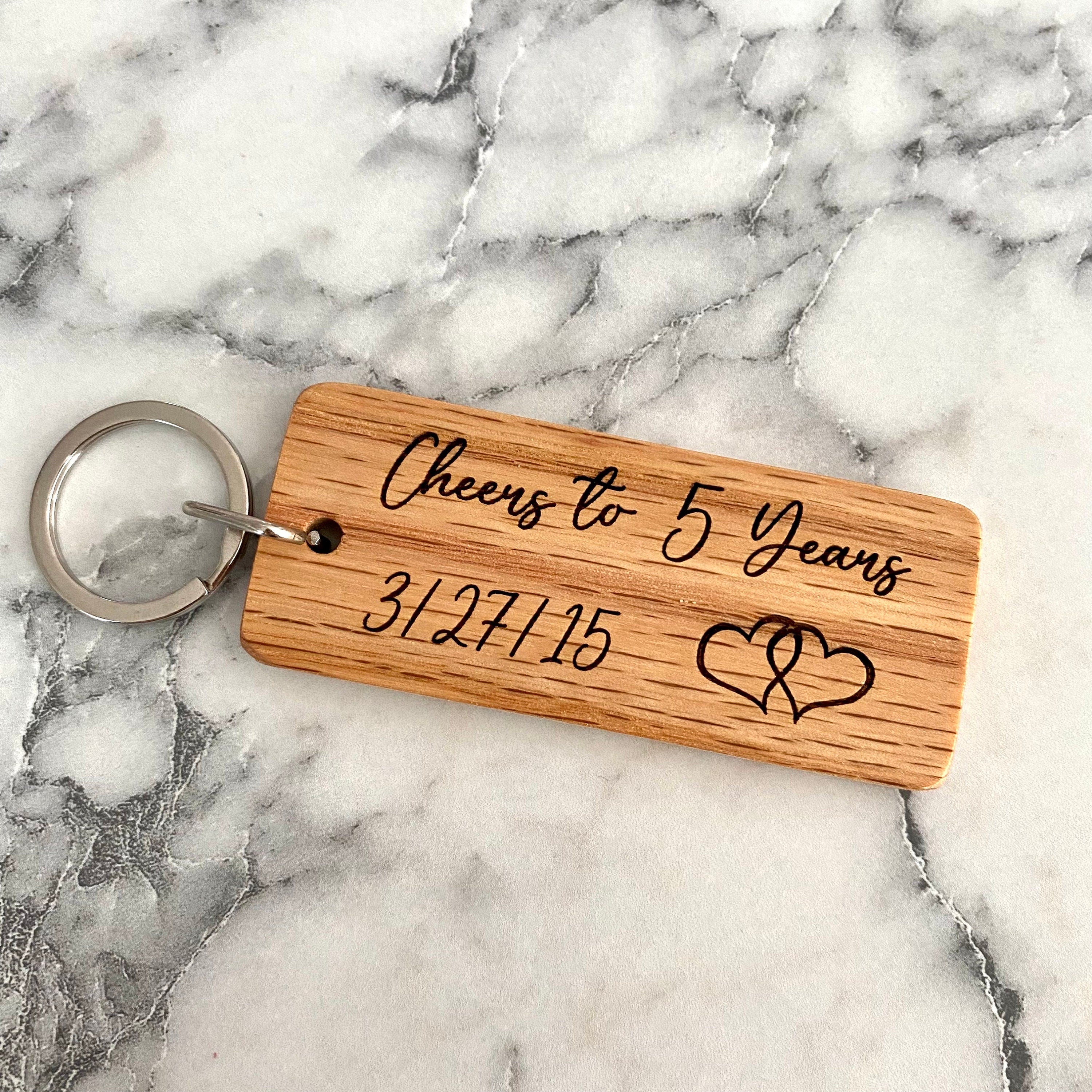 Engraved wood keychain featuring hearts and a custom date, perfect for 5-year anniversary gifts.