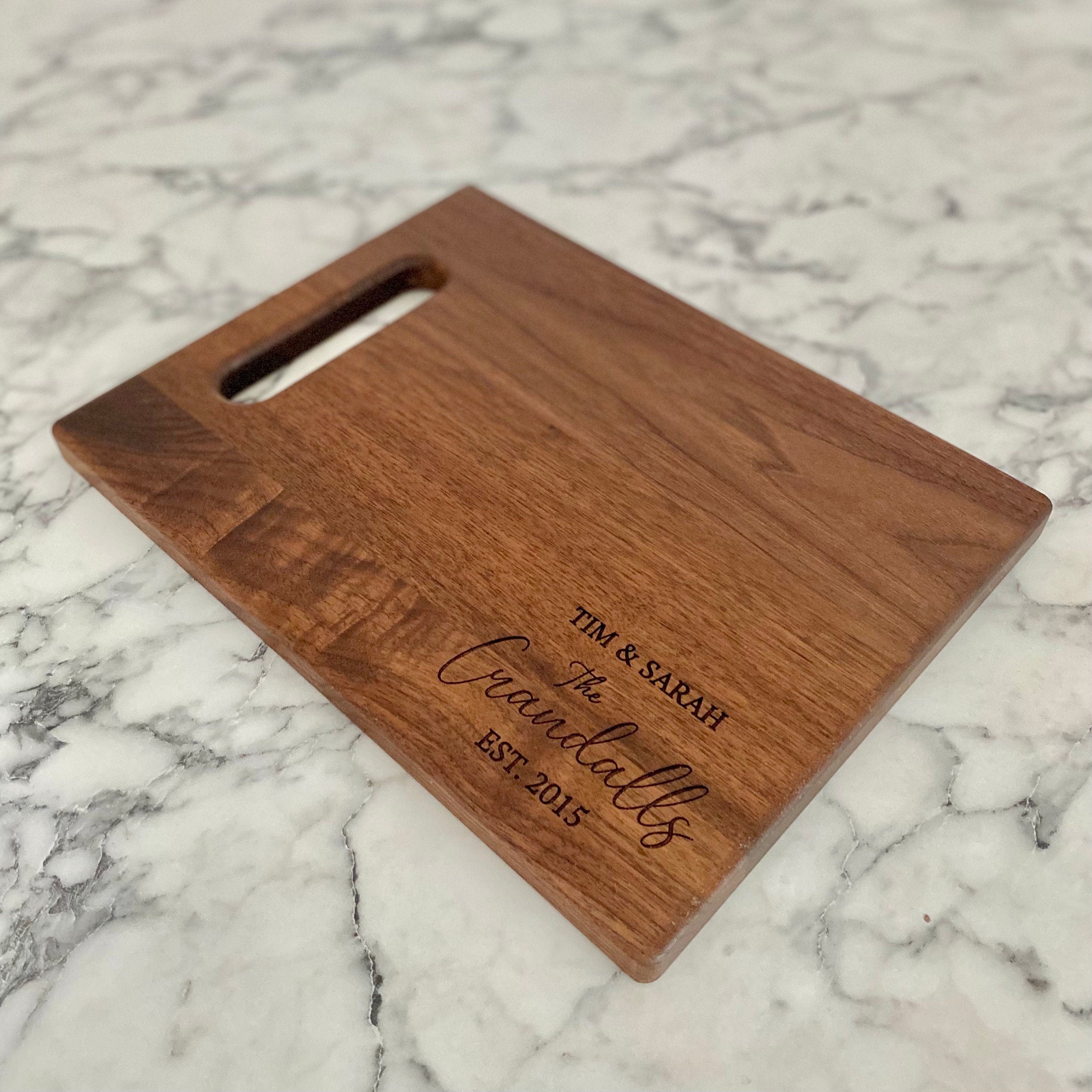 A beautifully engraved walnut wood cutting board measuring 9x12 inches, featuring a handle and custom design options.