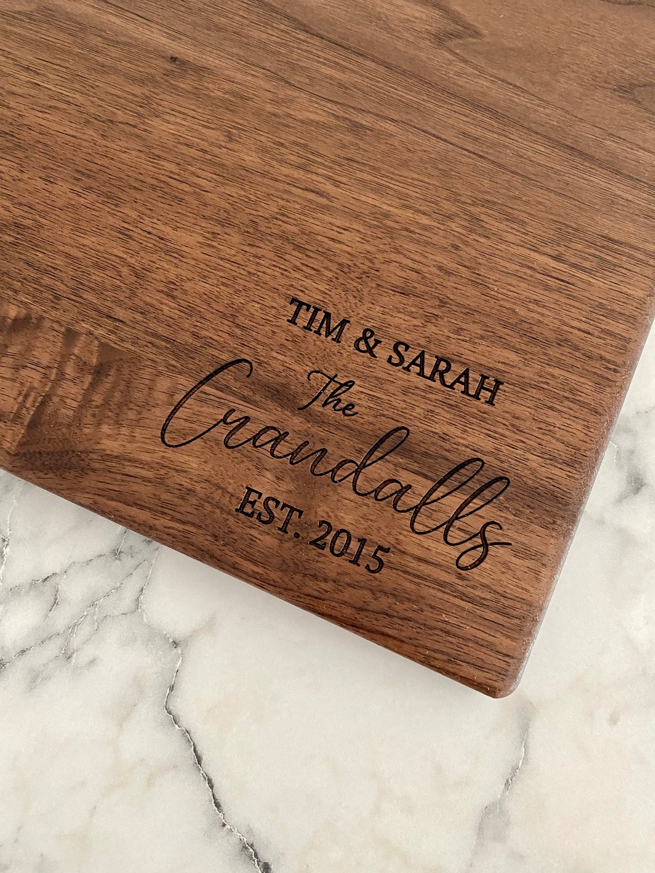 A beautifully engraved walnut wood cutting board measuring 9x12 inches, featuring a handle and custom design options.