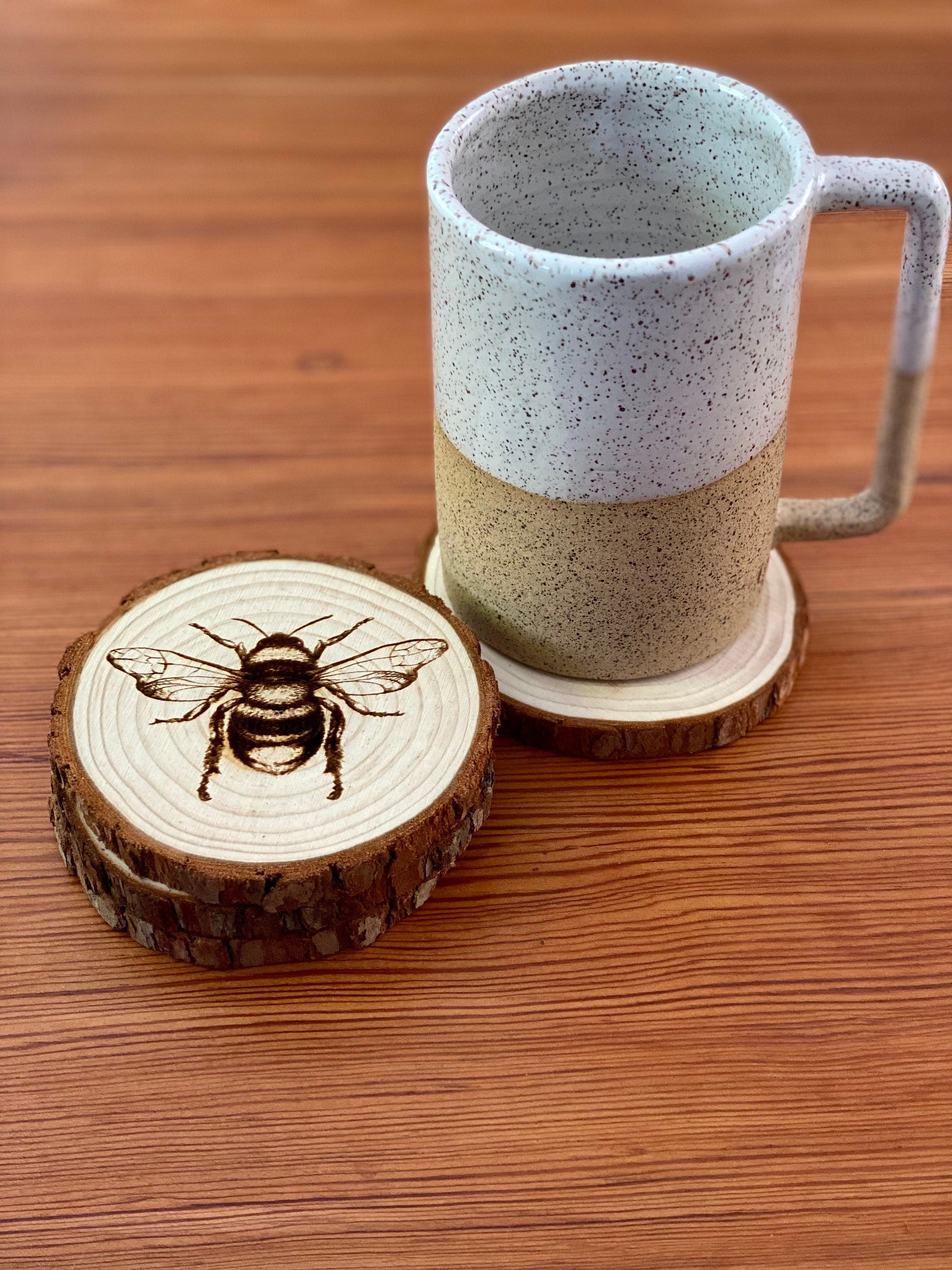 A set of four laser engraved wood coasters featuring intricate bee illustrations, showcasing their natural wood finish and unique designs.