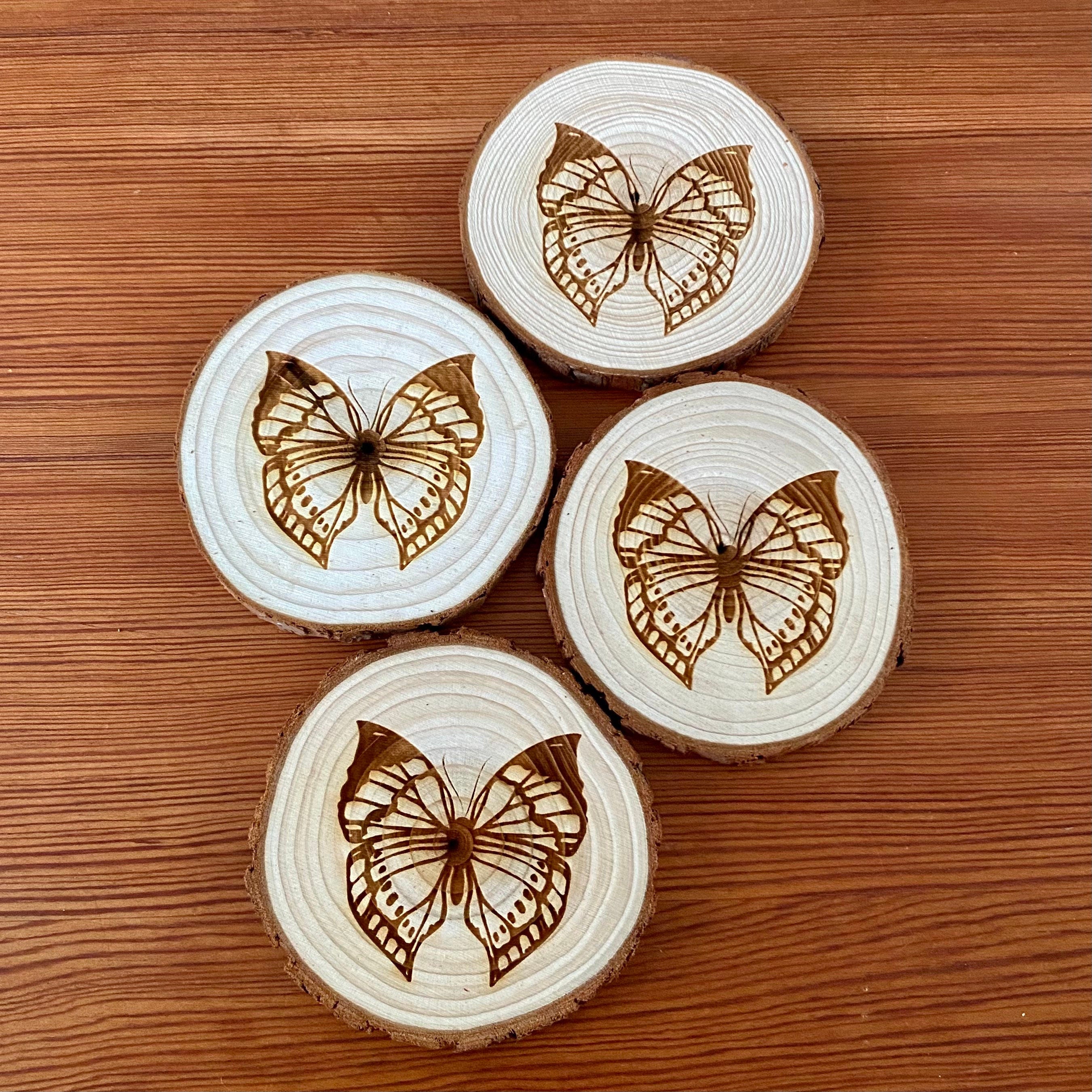 A set of four butterfly engraved wood coasters on a rustic wooden table, showcasing intricate butterfly designs.