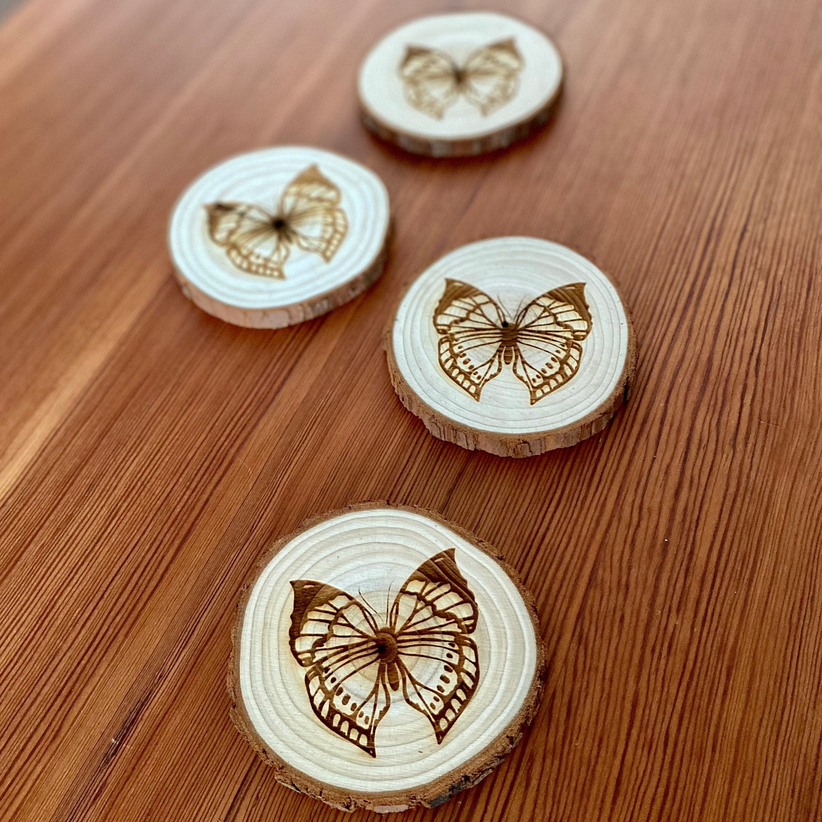 A set of four butterfly engraved wood coasters on a rustic wooden table, showcasing intricate butterfly designs.