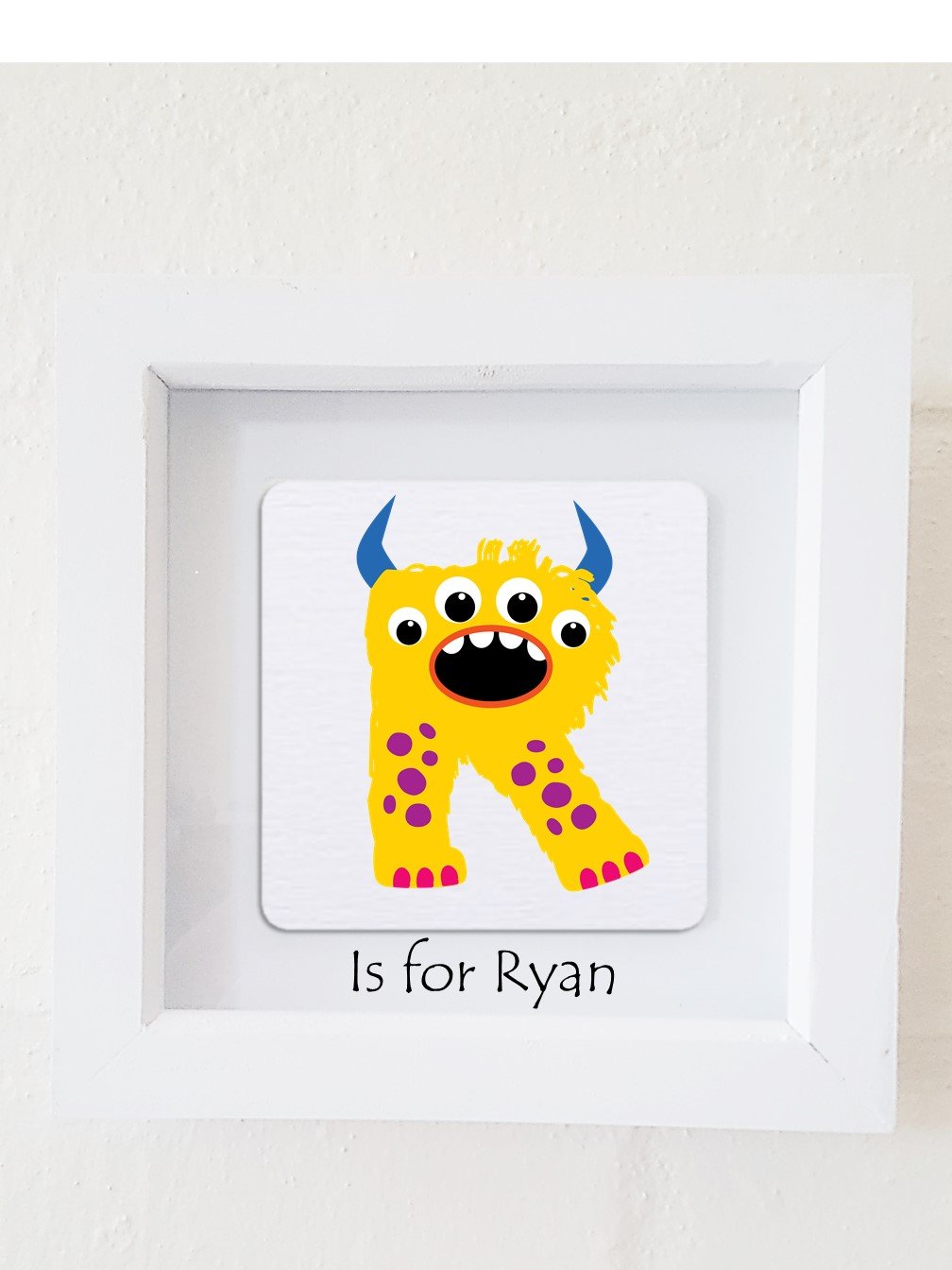 A colorful framed plaque featuring a monster design, personalized with a child's initial and name, perfect for children's bedroom decor.