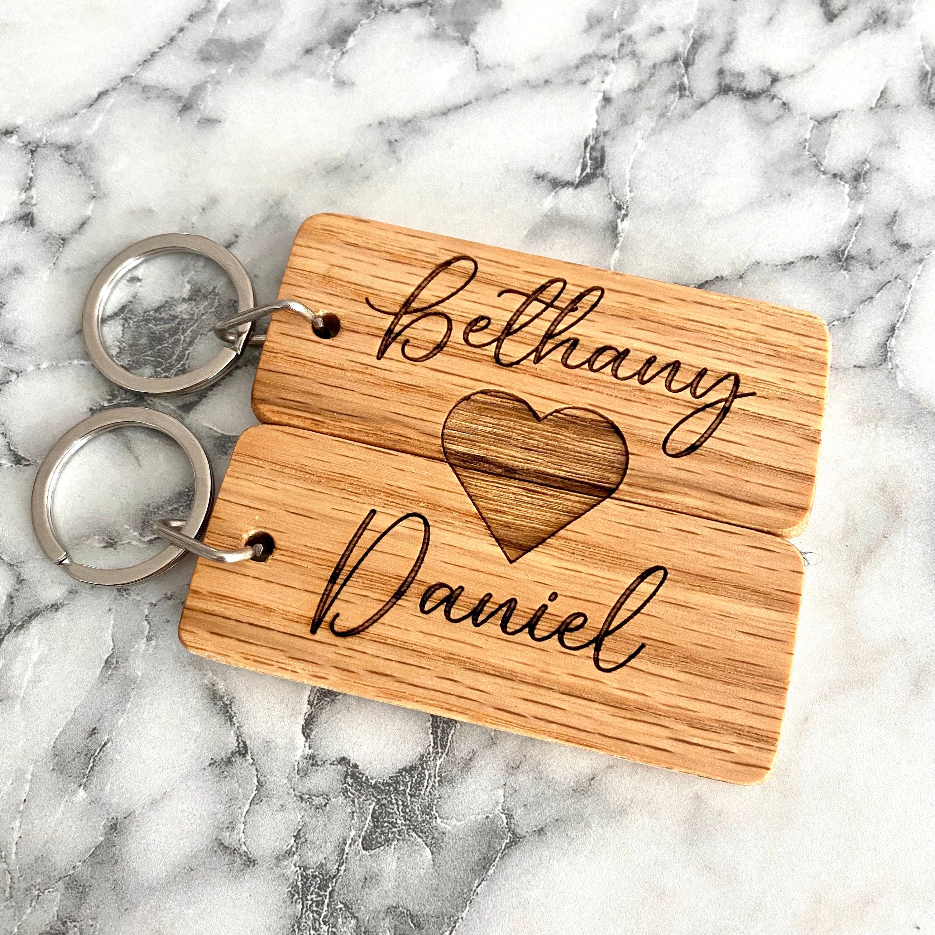 Couples Engraved Wood Keychain set featuring personalized names and a joined heart design, crafted from solid hardwood oak.