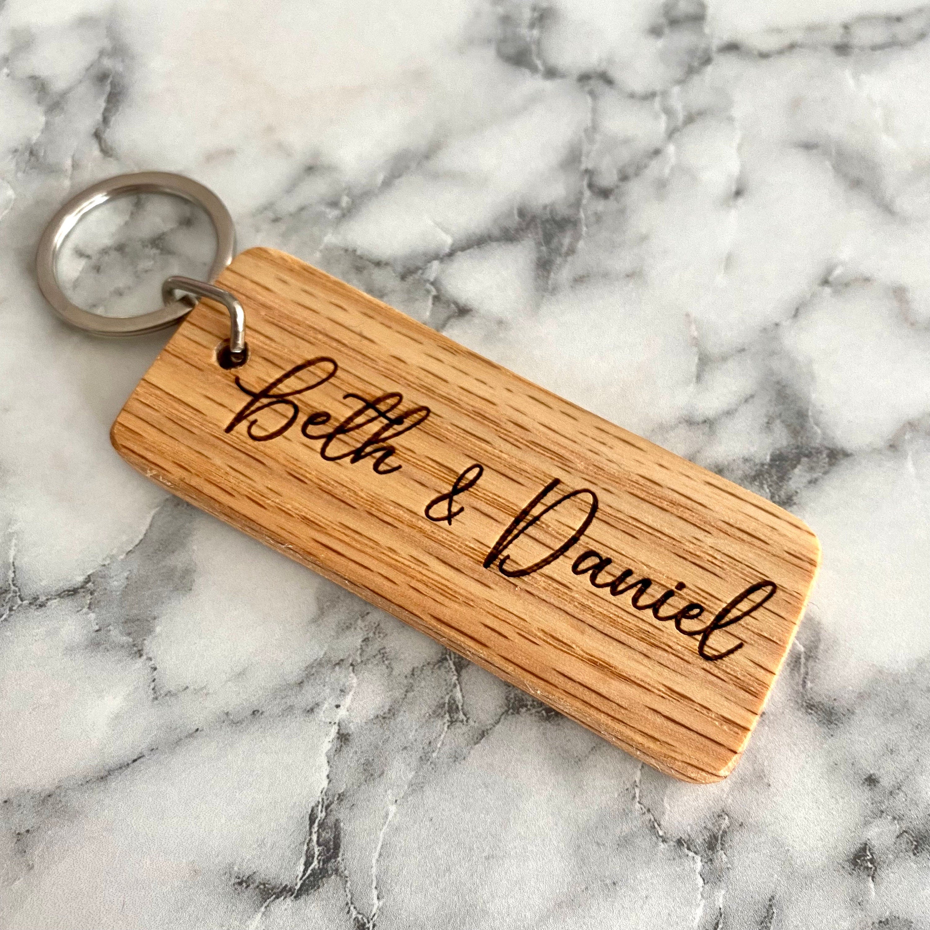 Personalized wood keychain engraved with couple's names, made from solid oak, showcasing a rustic and elegant design.