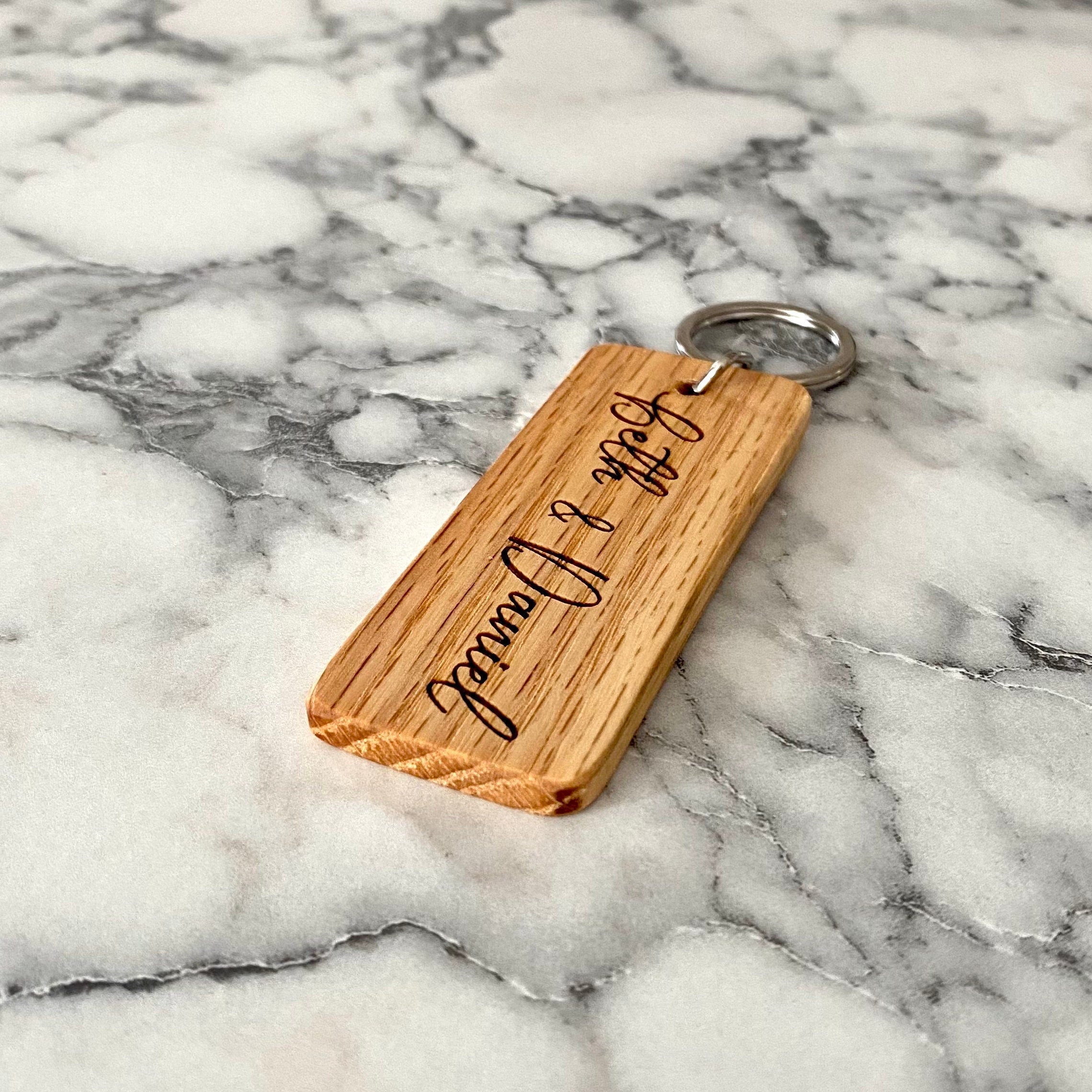 Personalized wood keychain engraved with couple's names, made from solid oak, showcasing a rustic and elegant design.