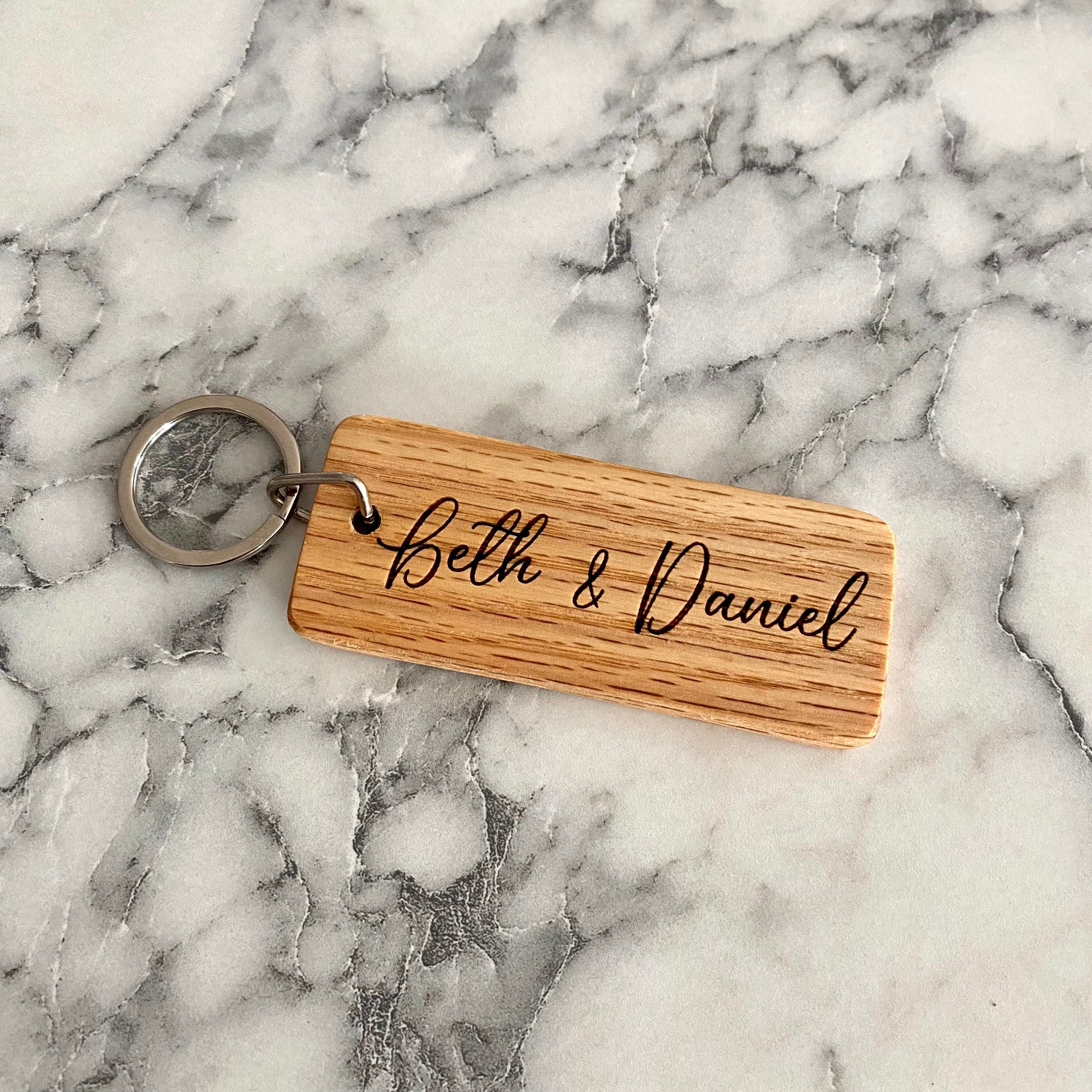 Personalized wood keychain engraved with couple's names, made from solid oak, showcasing a rustic and elegant design.