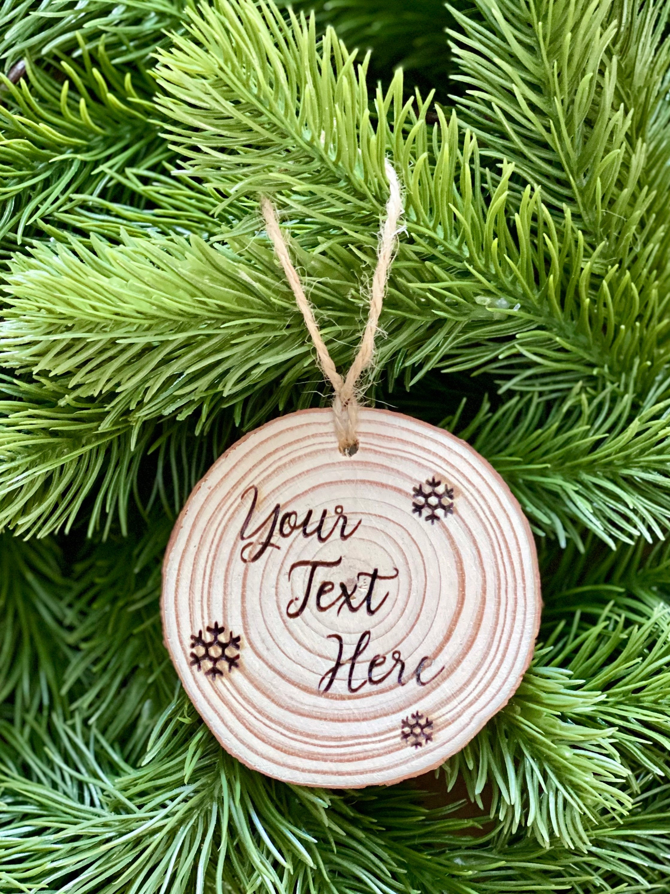 Custom engraved wood slice Christmas ornament with snowflake and holly designs, showcasing rustic charm.