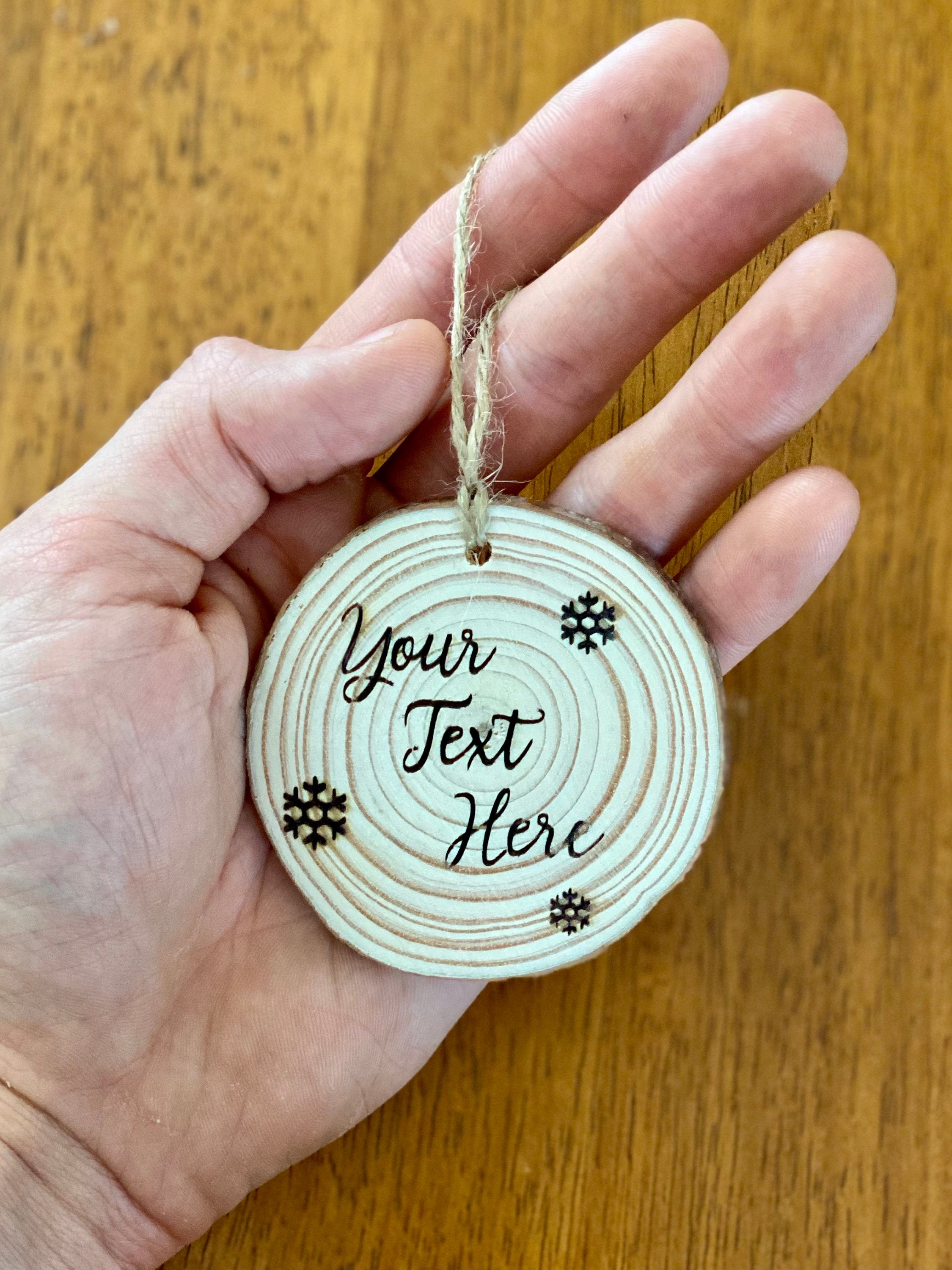 Custom engraved wood slice Christmas ornament with snowflake and holly designs, showcasing rustic charm.