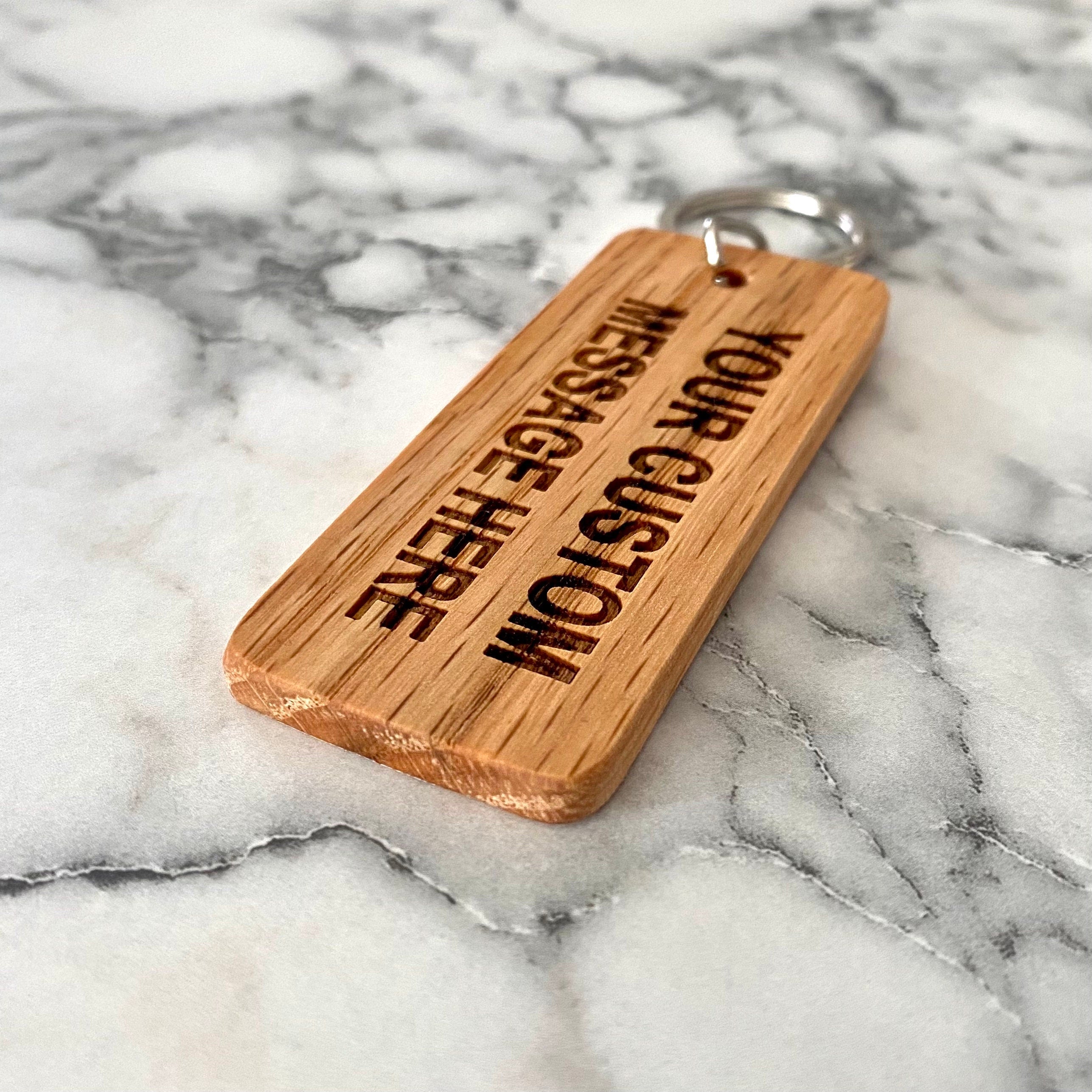 Custom engraved wood keychain made from solid oak, featuring personalized text and a smooth finish.