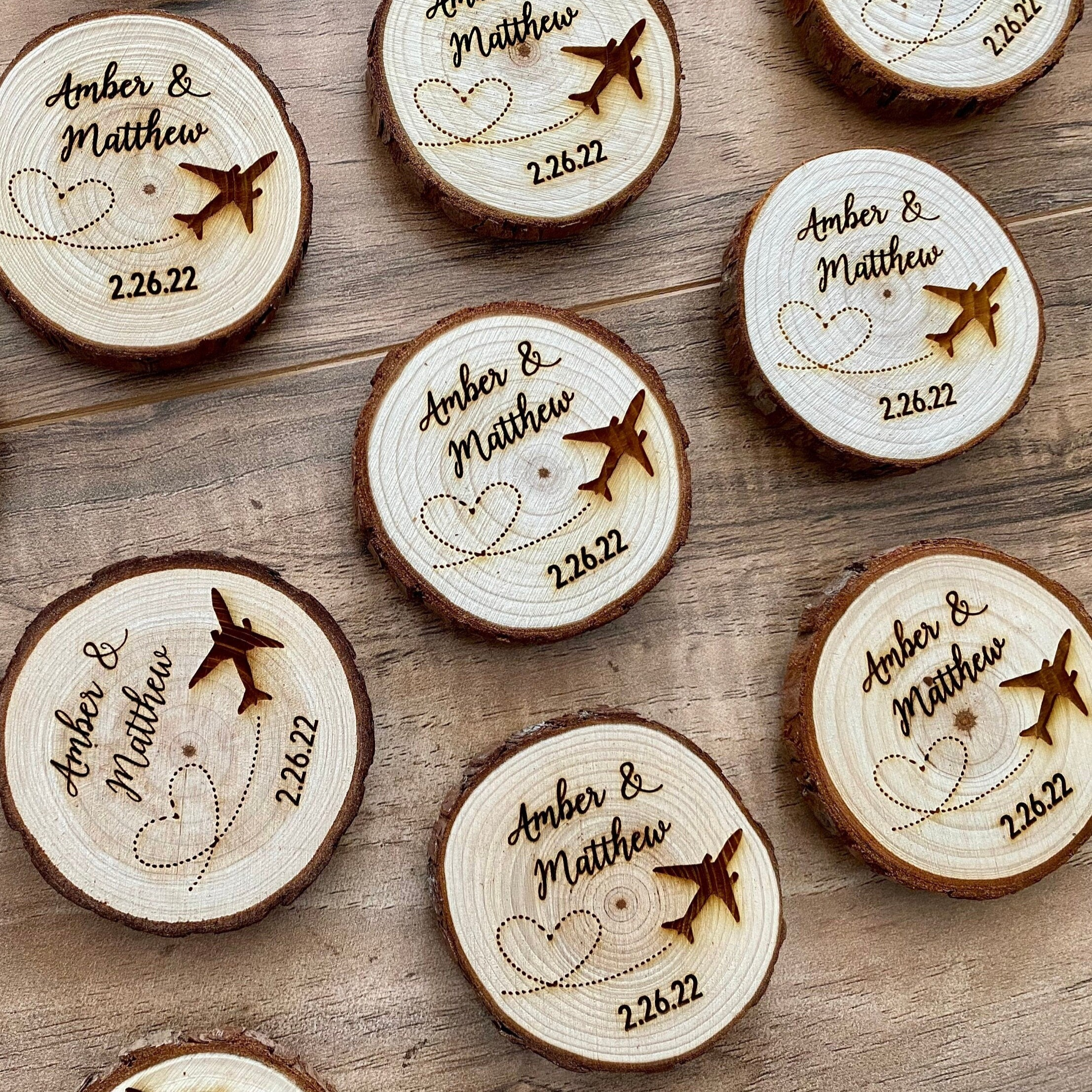 Personalized wood slice wedding favor featuring airplane design, engraved with couple's names and wedding date, with a magnet on the back.