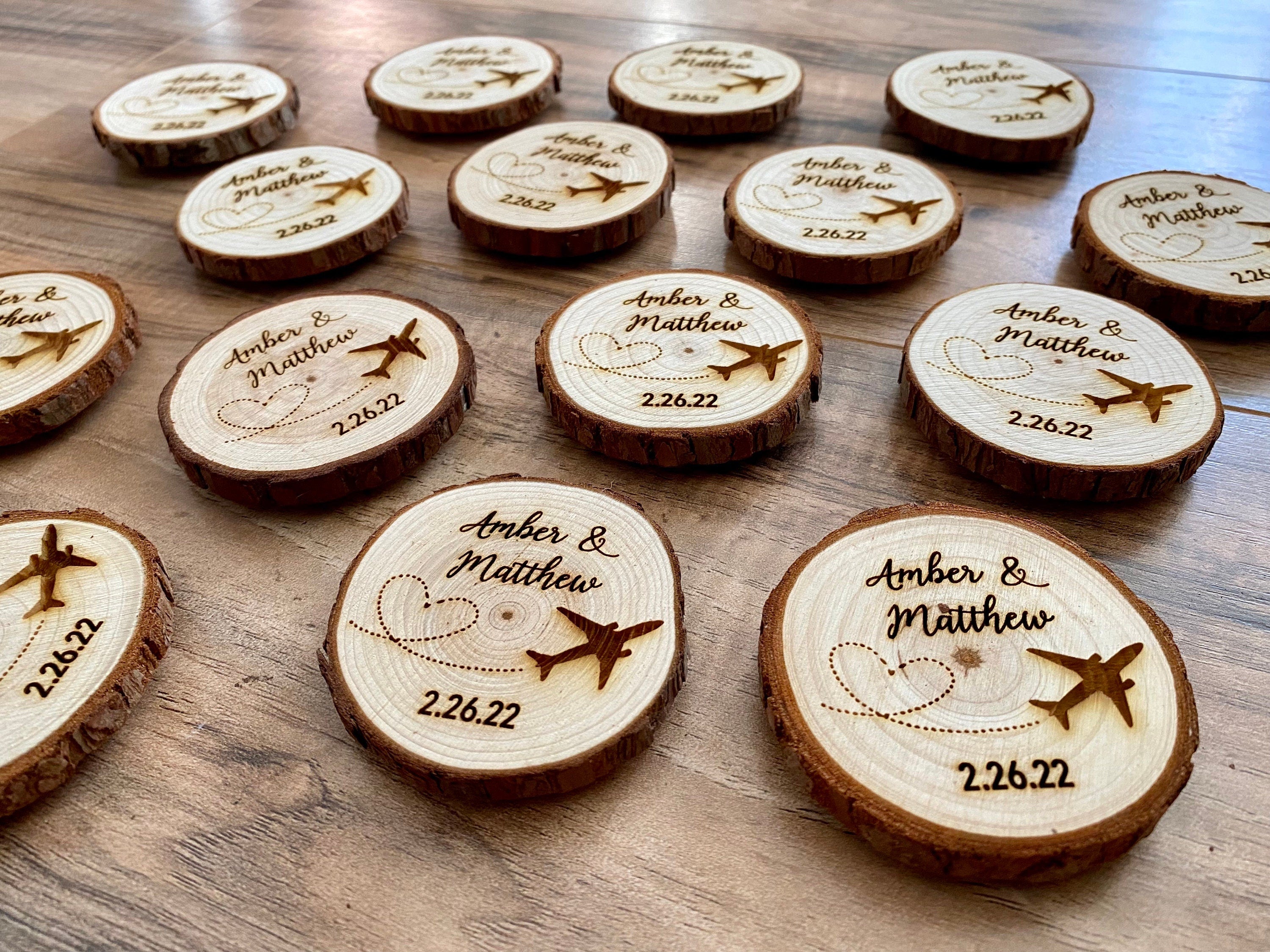 Personalized wood slice wedding favor featuring airplane design, engraved with couple's names and wedding date, with a magnet on the back.