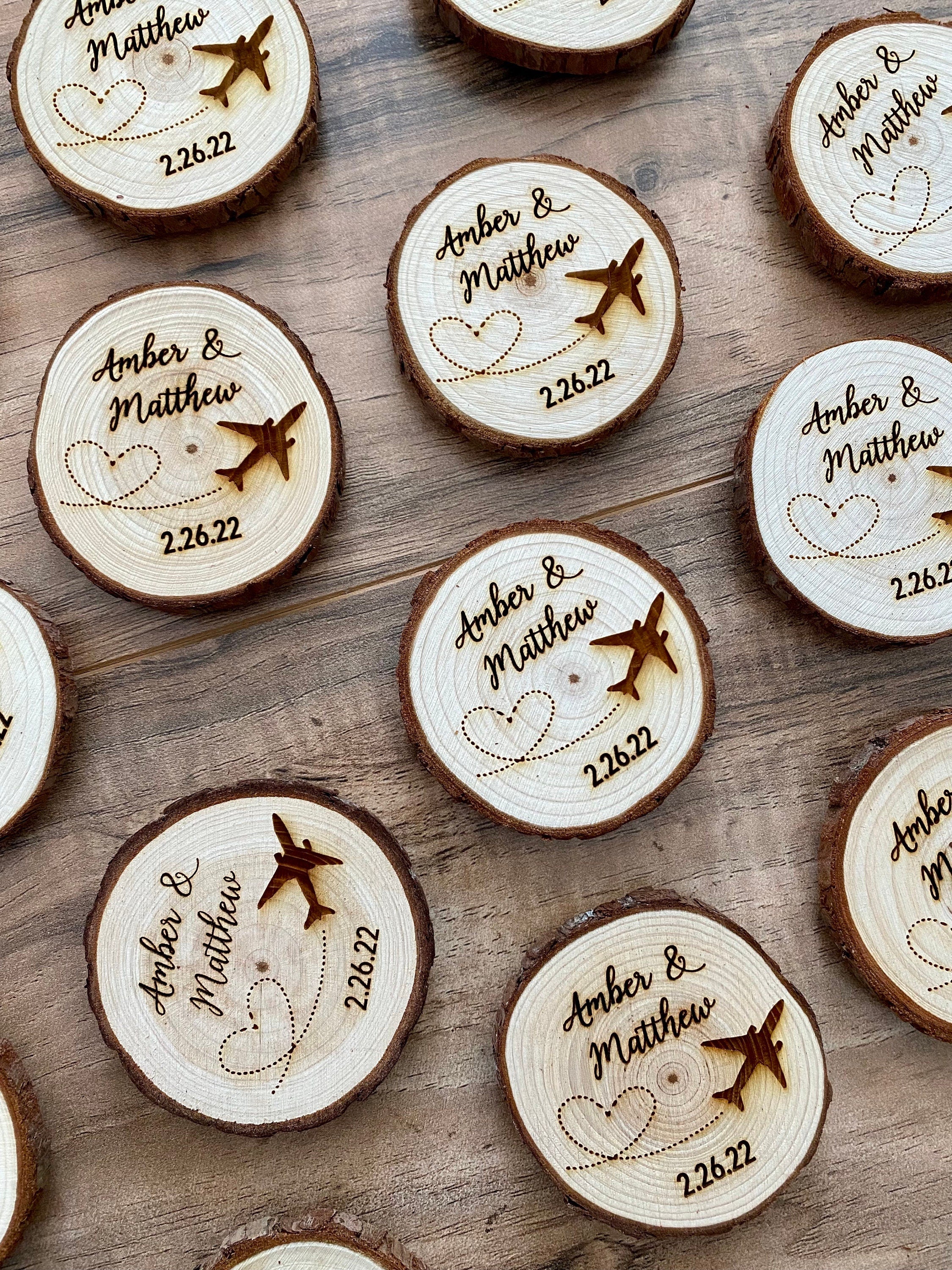 Personalized wood slice wedding favor featuring airplane design, engraved with couple's names and wedding date, with a magnet on the back.