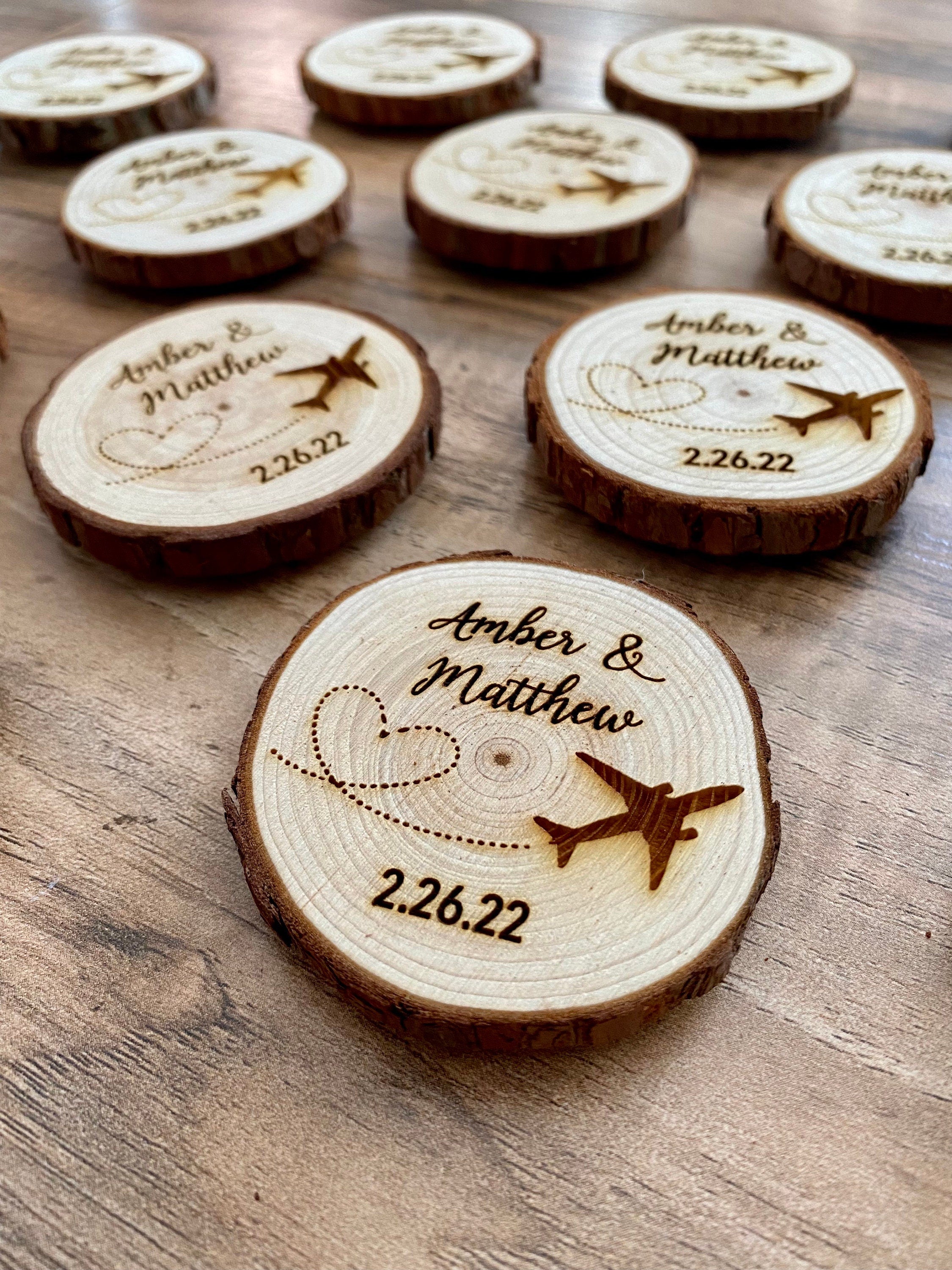 Personalized wood slice wedding favor featuring airplane design, engraved with couple's names and wedding date, with a magnet on the back.