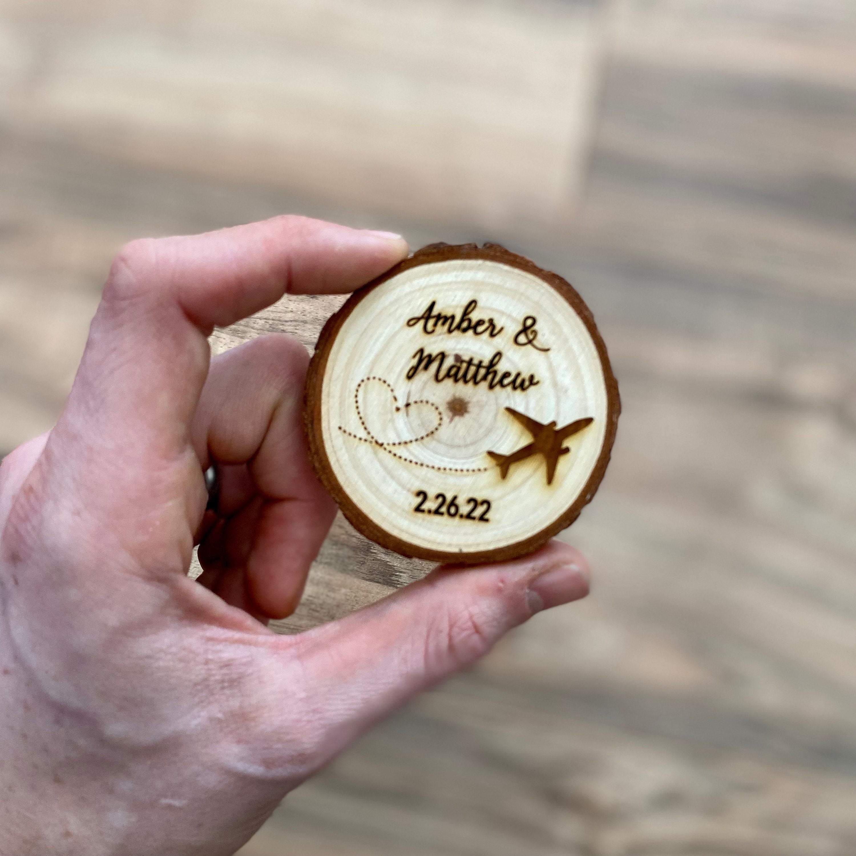 Personalized wood slice wedding favor featuring airplane design, engraved with couple's names and wedding date, with a magnet on the back.