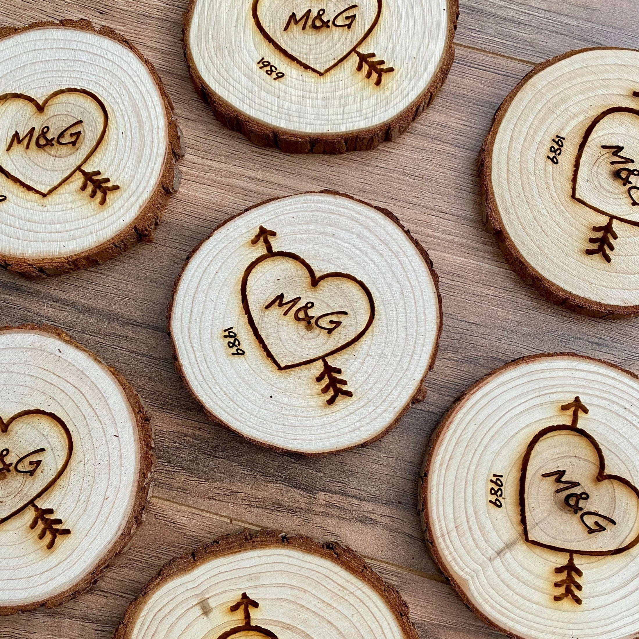 Custom wood slice wedding favors featuring heart and arrow design with initials and date engraved.