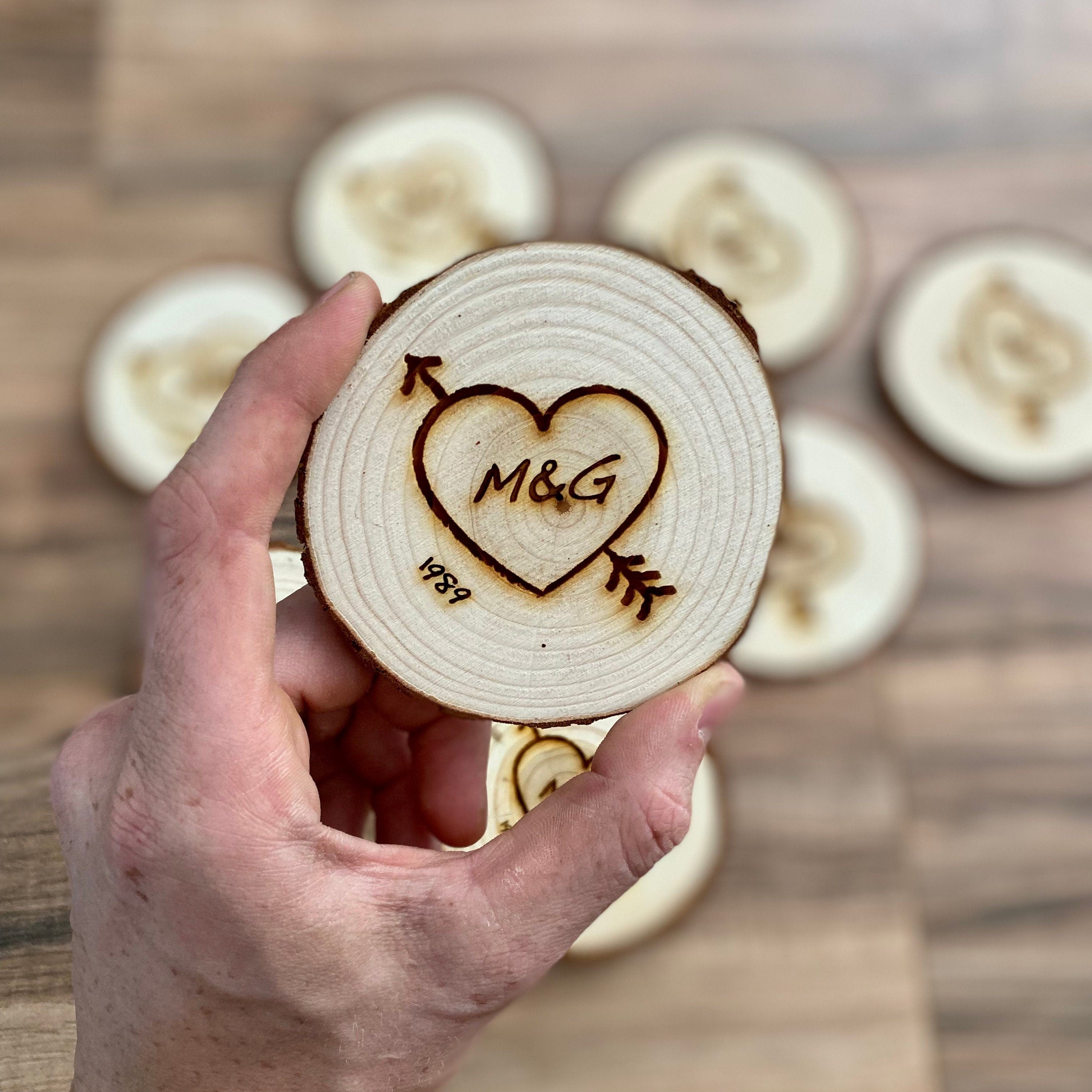 Custom wood slice wedding favors featuring heart and arrow design with initials and date engraved.