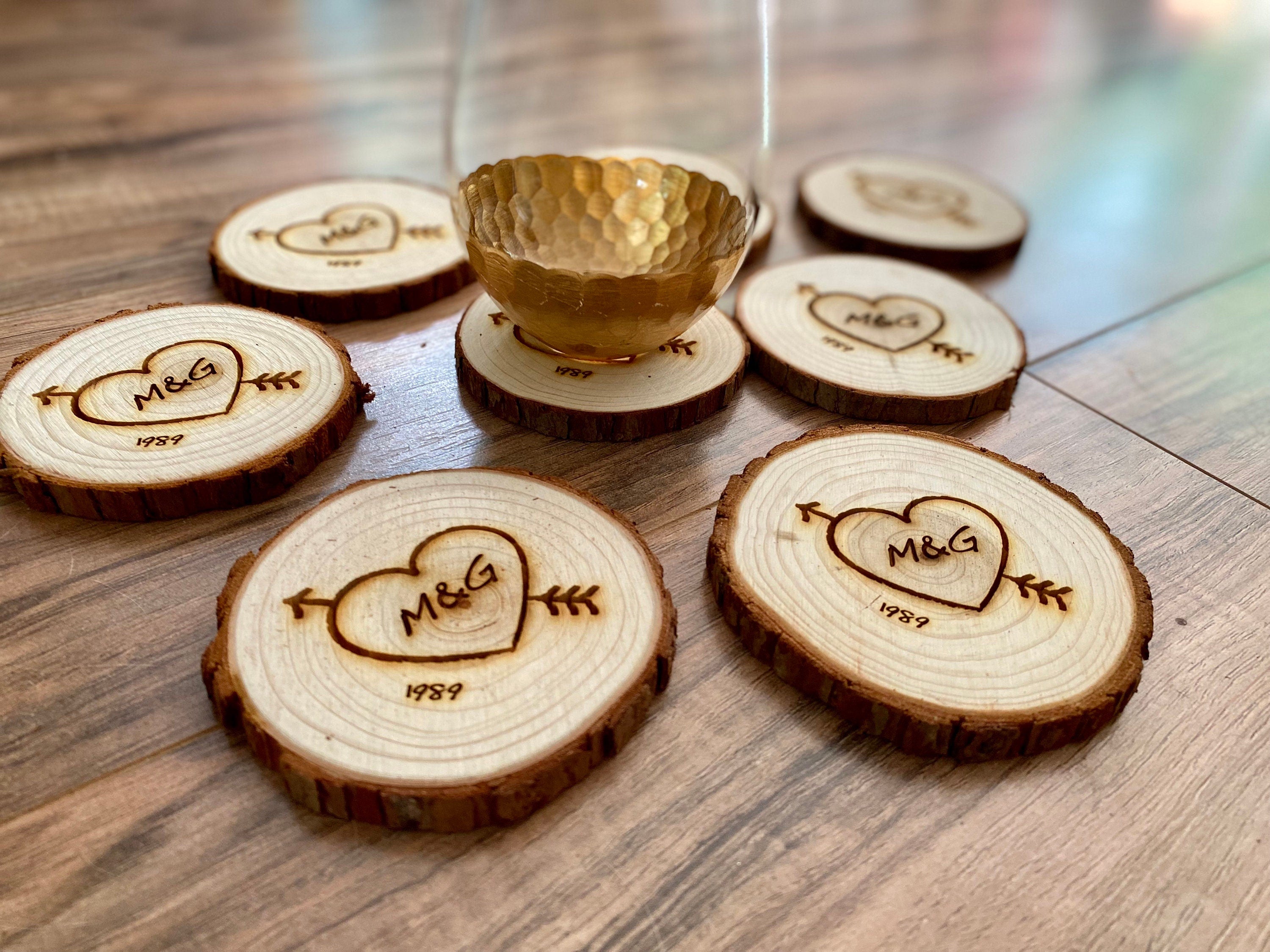 Custom wood slice wedding favors featuring heart and arrow design with initials and date engraved.