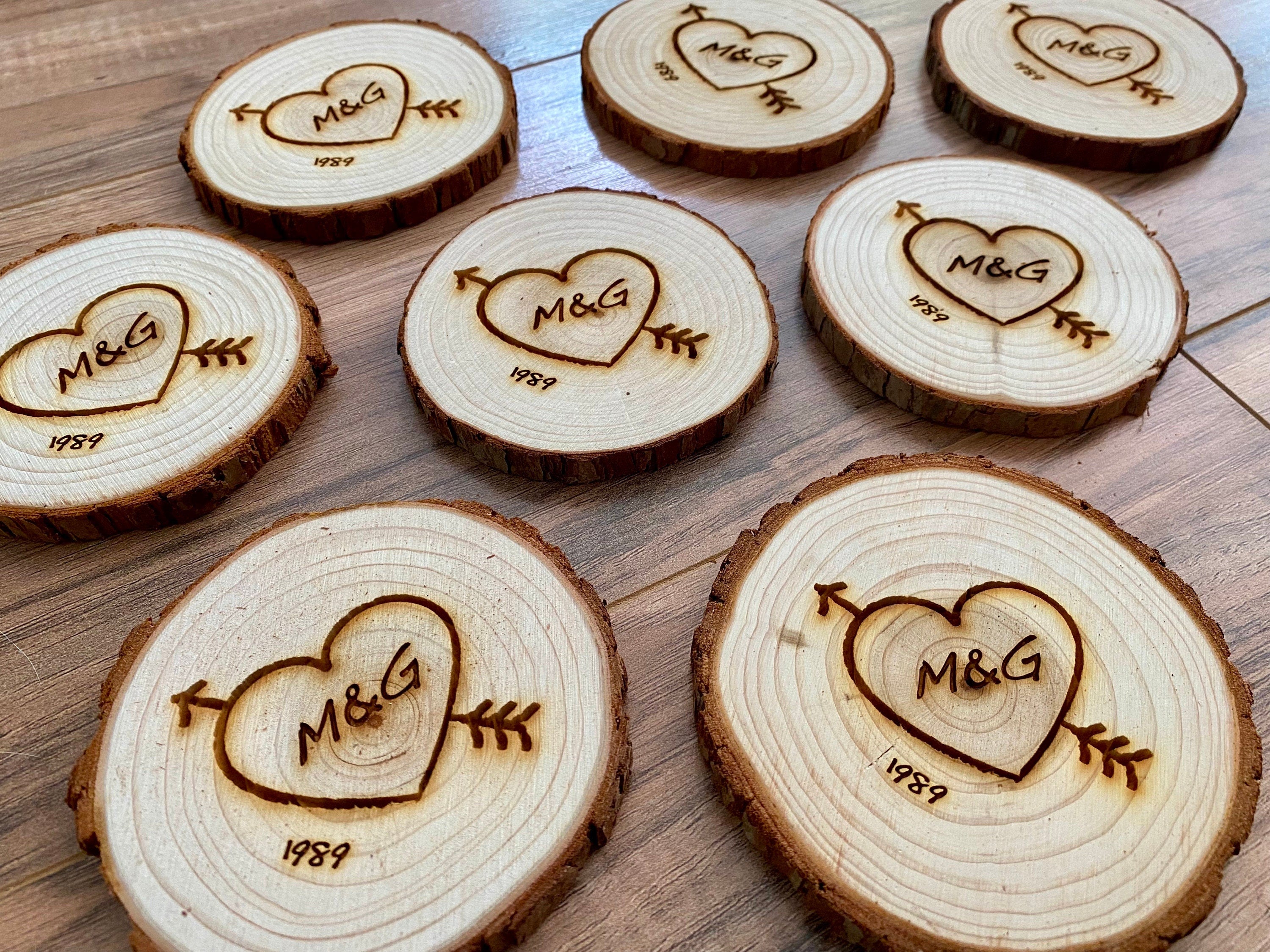 Custom wood slice wedding favors featuring heart and arrow design with initials and date engraved.