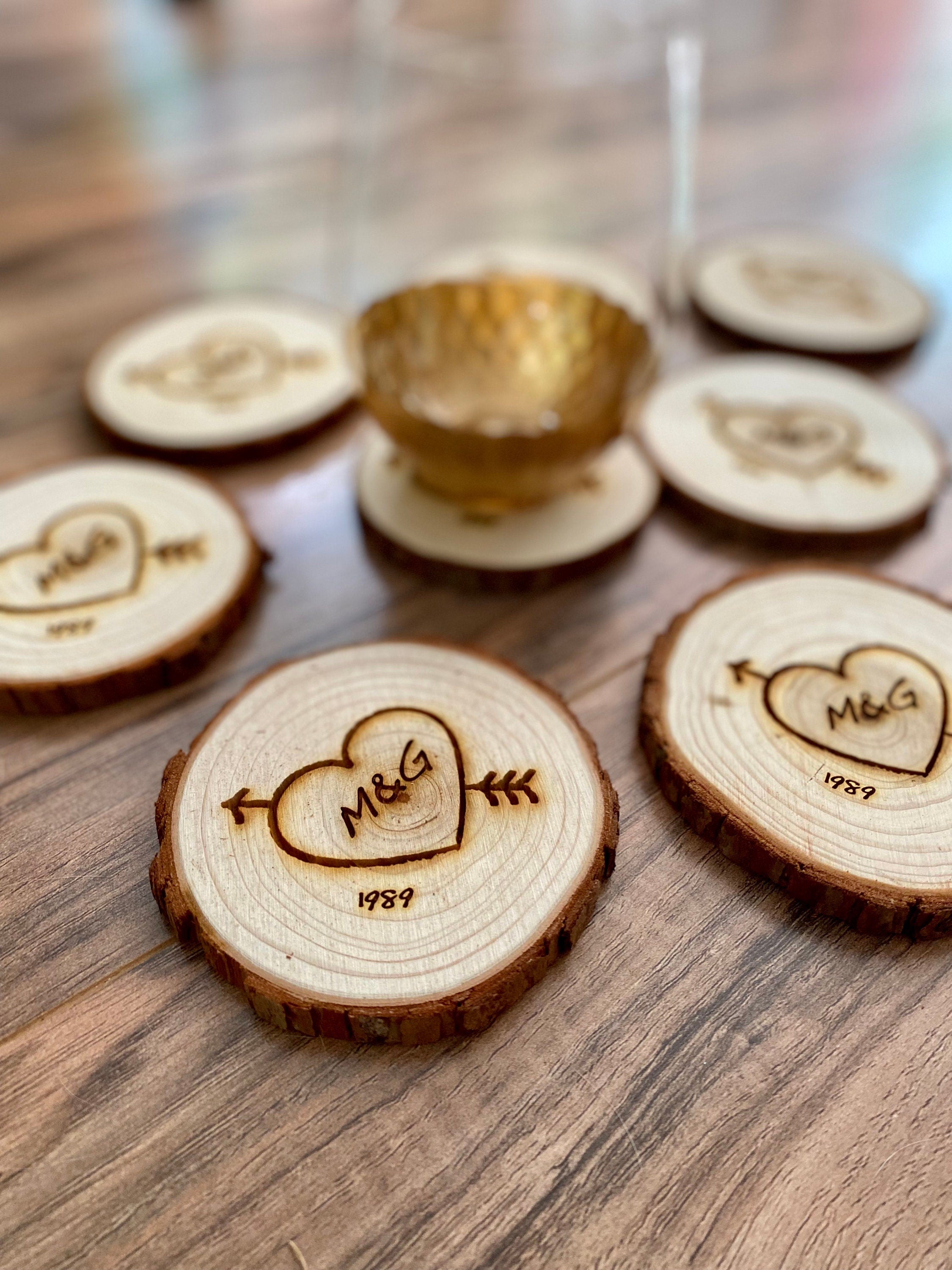 Custom wood slice wedding favors featuring heart and arrow design with initials and date engraved.