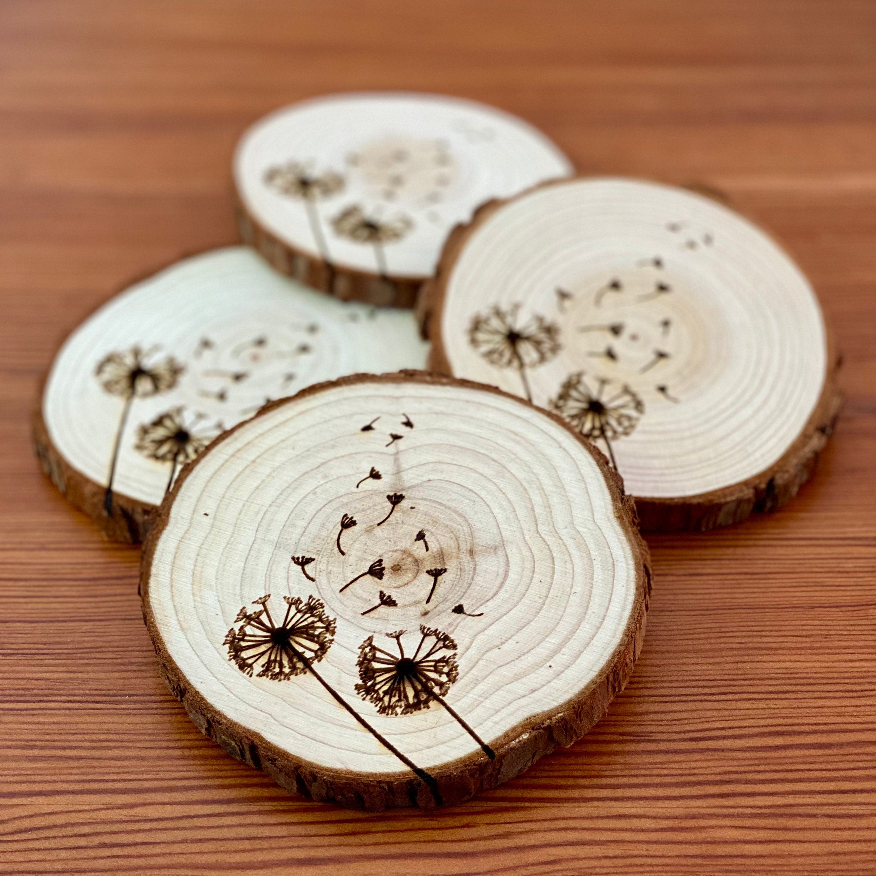 A set of four laser engraved wood coasters featuring intricate dandelion designs, showcasing their natural wood finish and unique textures.