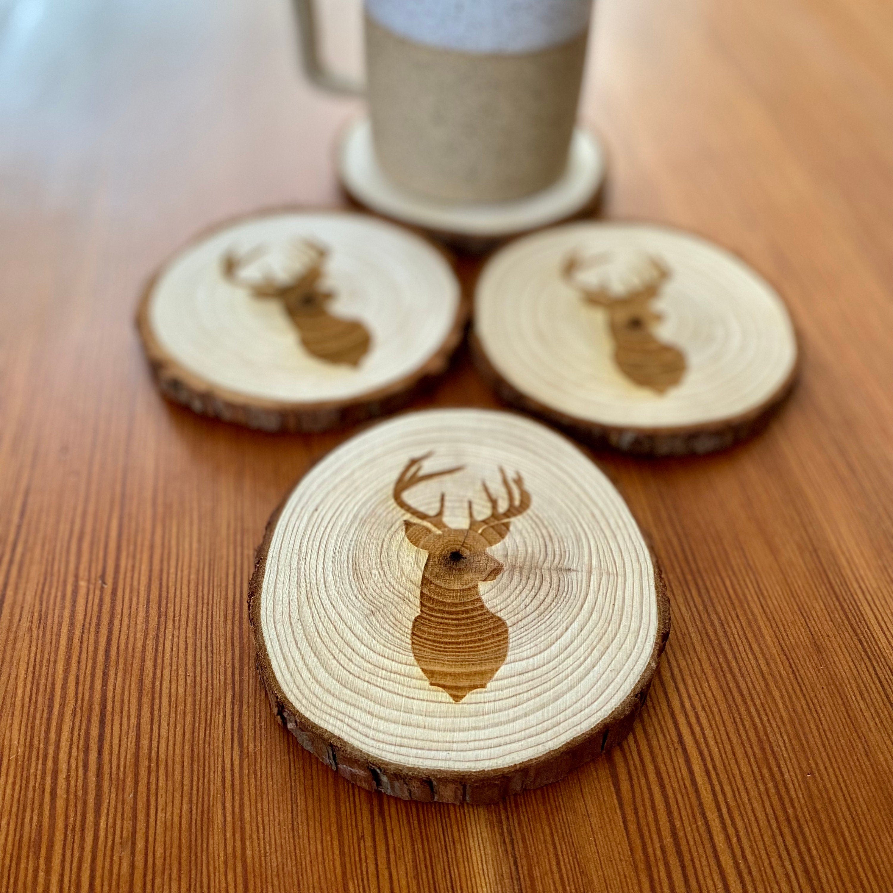 A set of four laser engraved wood coasters featuring a deer head silhouette, showcasing their natural wood finish and unique design.