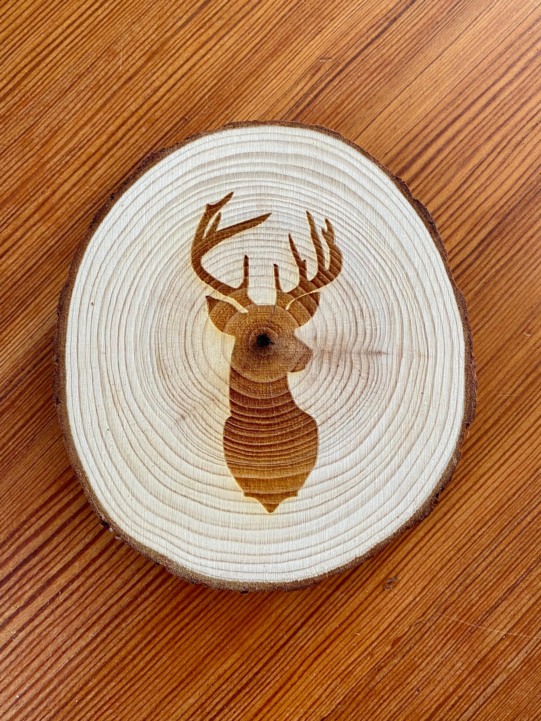 A set of four laser engraved wood coasters featuring a deer head silhouette, showcasing their natural wood finish and unique design.