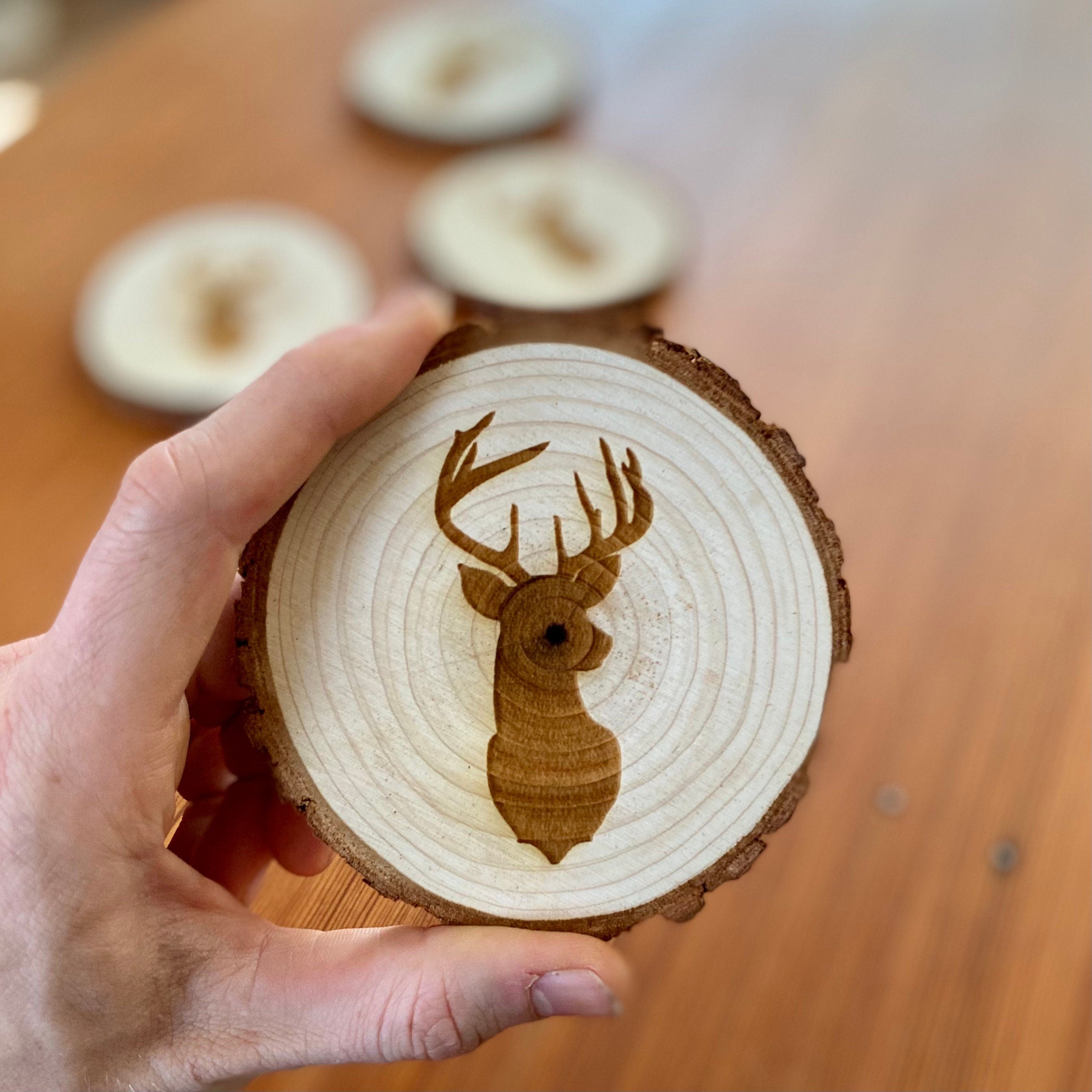 A set of four laser engraved wood coasters featuring a deer head silhouette, showcasing their natural wood finish and unique design.