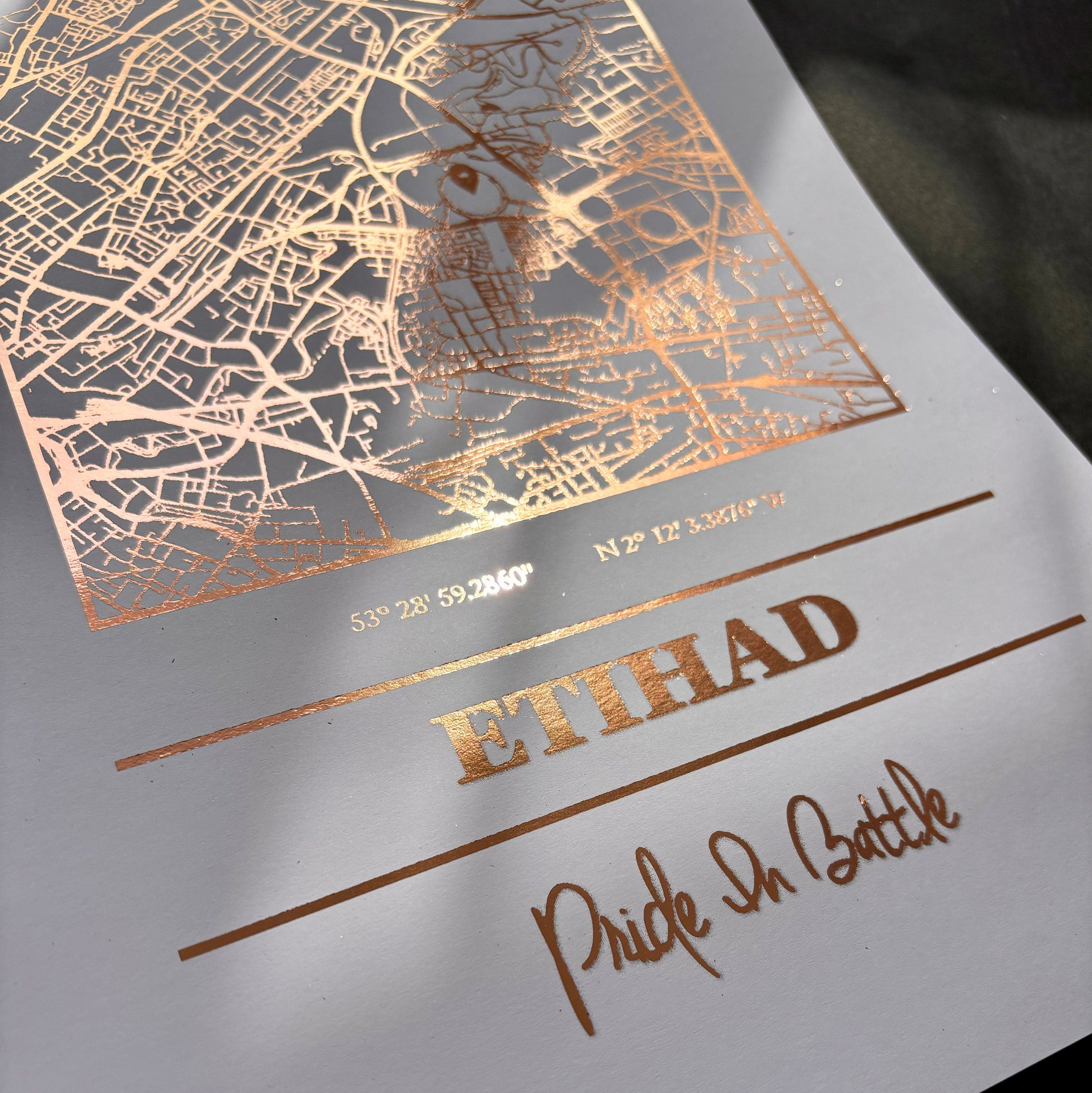 Etihad Foil Map Print featuring intricate foil detailing of Manchester City's stadium, showcasing coordinates and slogan.