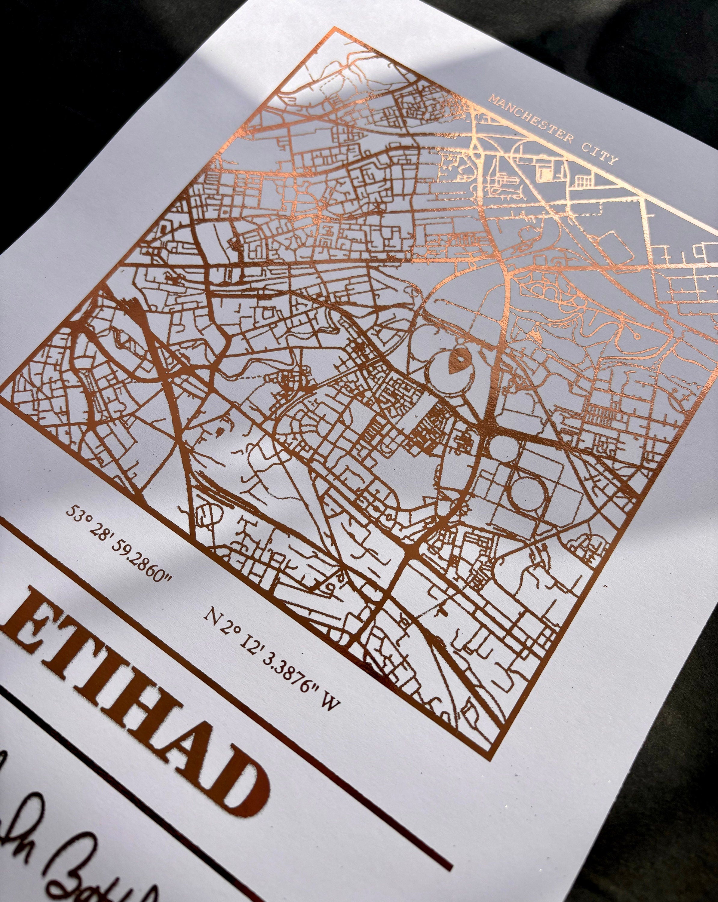 Etihad Foil Map Print featuring intricate foil detailing of Manchester City's stadium, showcasing coordinates and slogan.