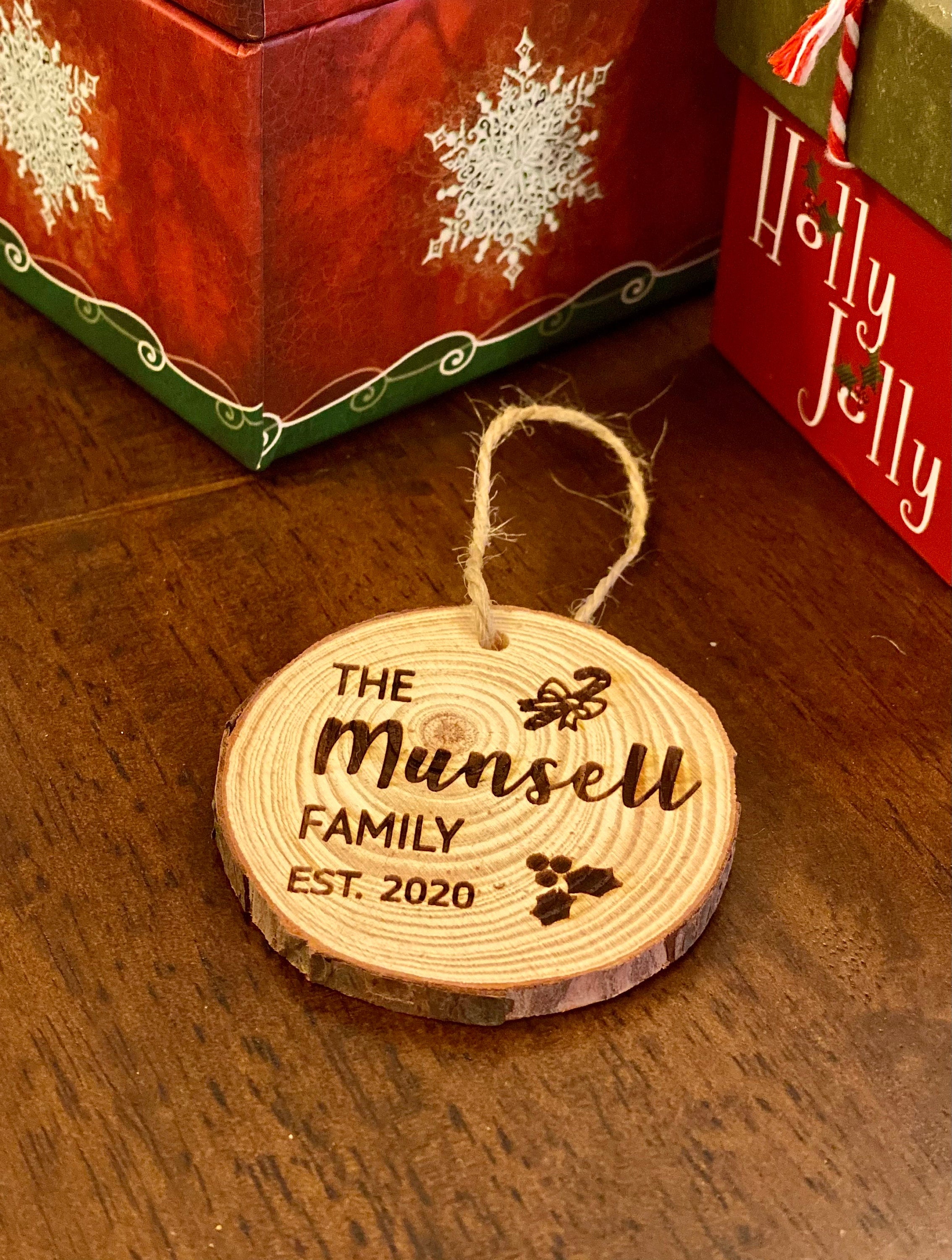 Engraved wood slice ornament featuring family name and year, decorated with candy cane and holly accents.