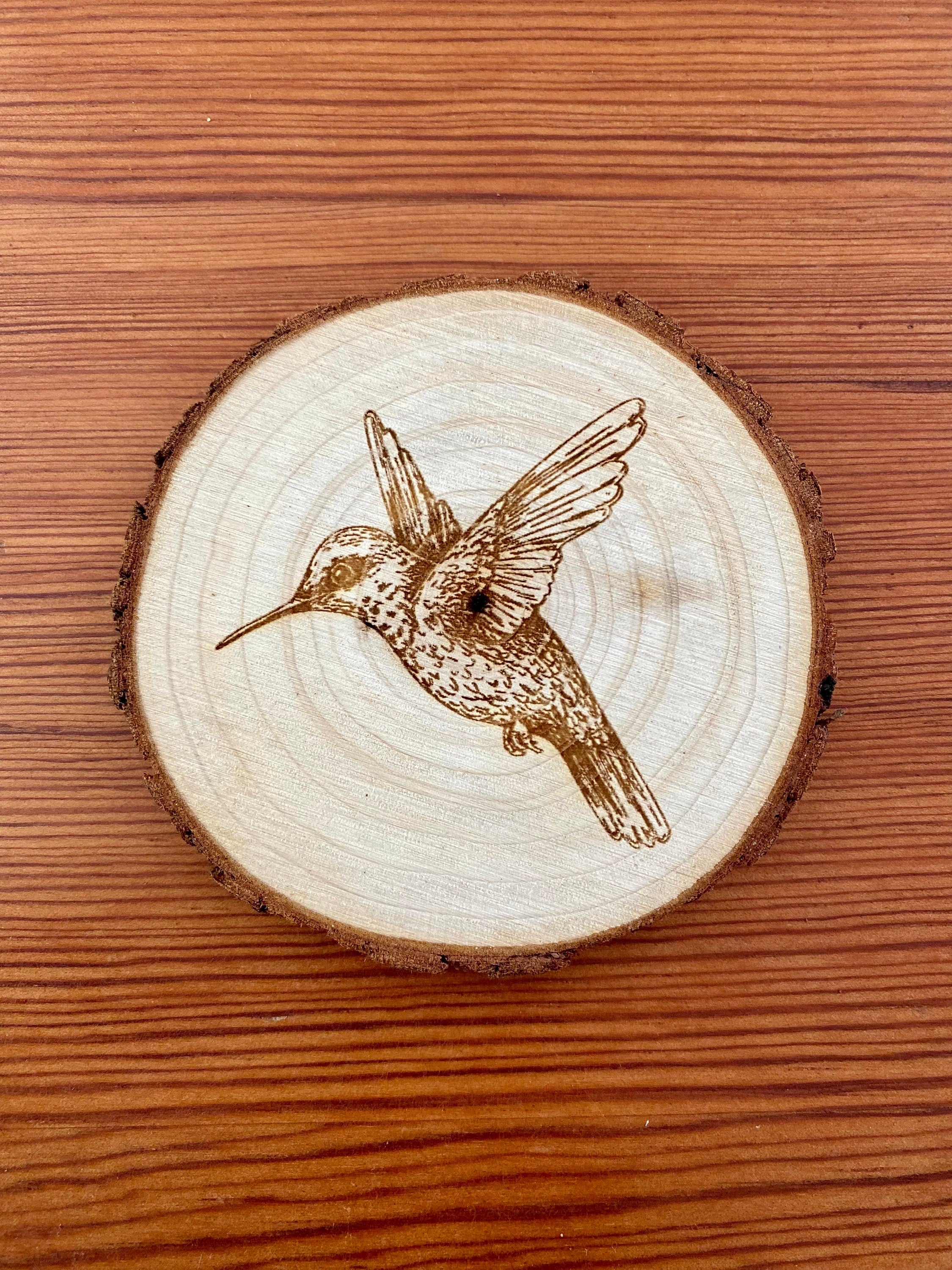 Set of four laser engraved wood coasters featuring intricate hummingbird designs, showcasing natural wood texture.