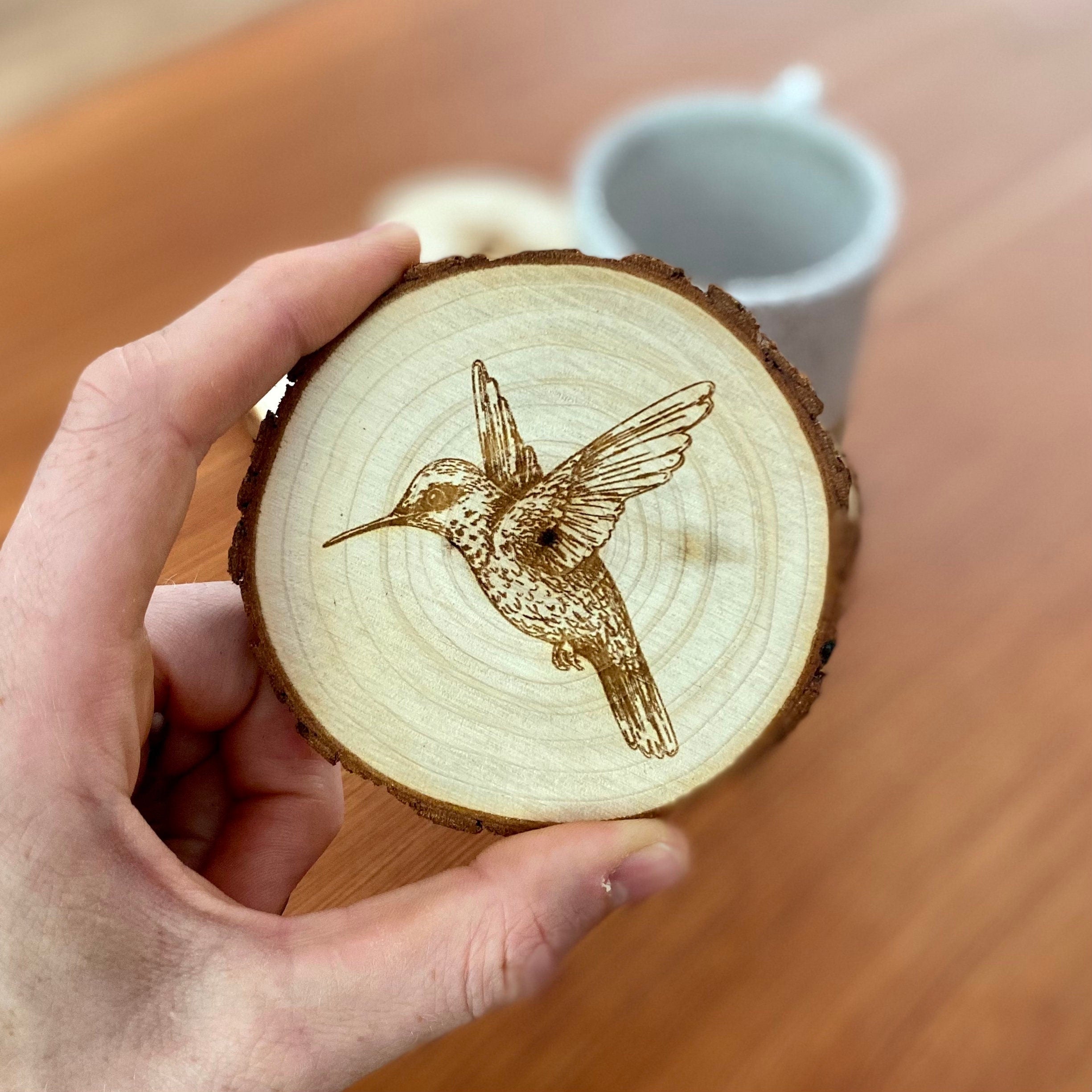 Set of four laser engraved wood coasters featuring intricate hummingbird designs, showcasing natural wood texture.