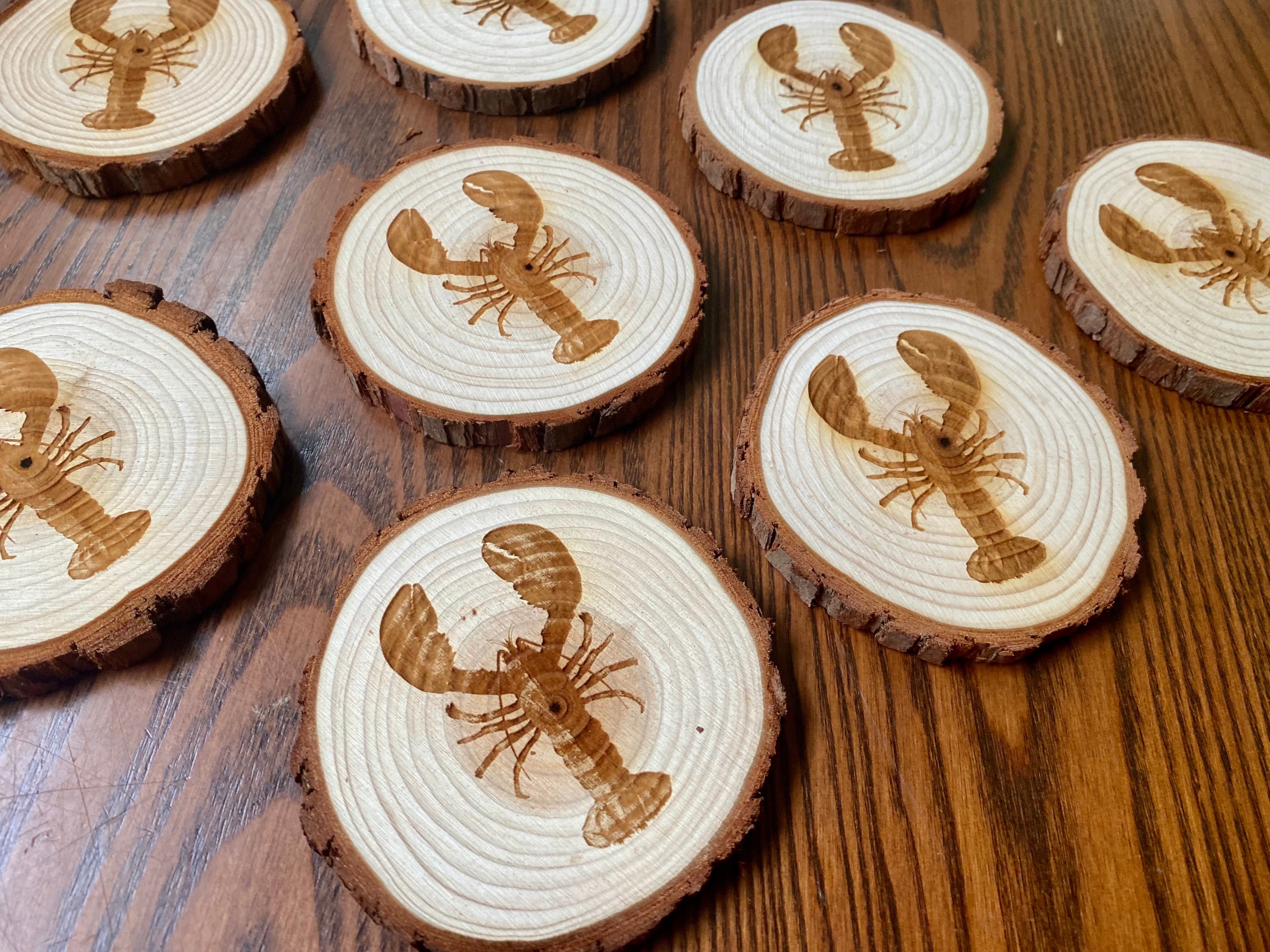 A set of four laser engraved wood coasters featuring intricate lobster designs, showcasing their natural wood finish and unique textures.