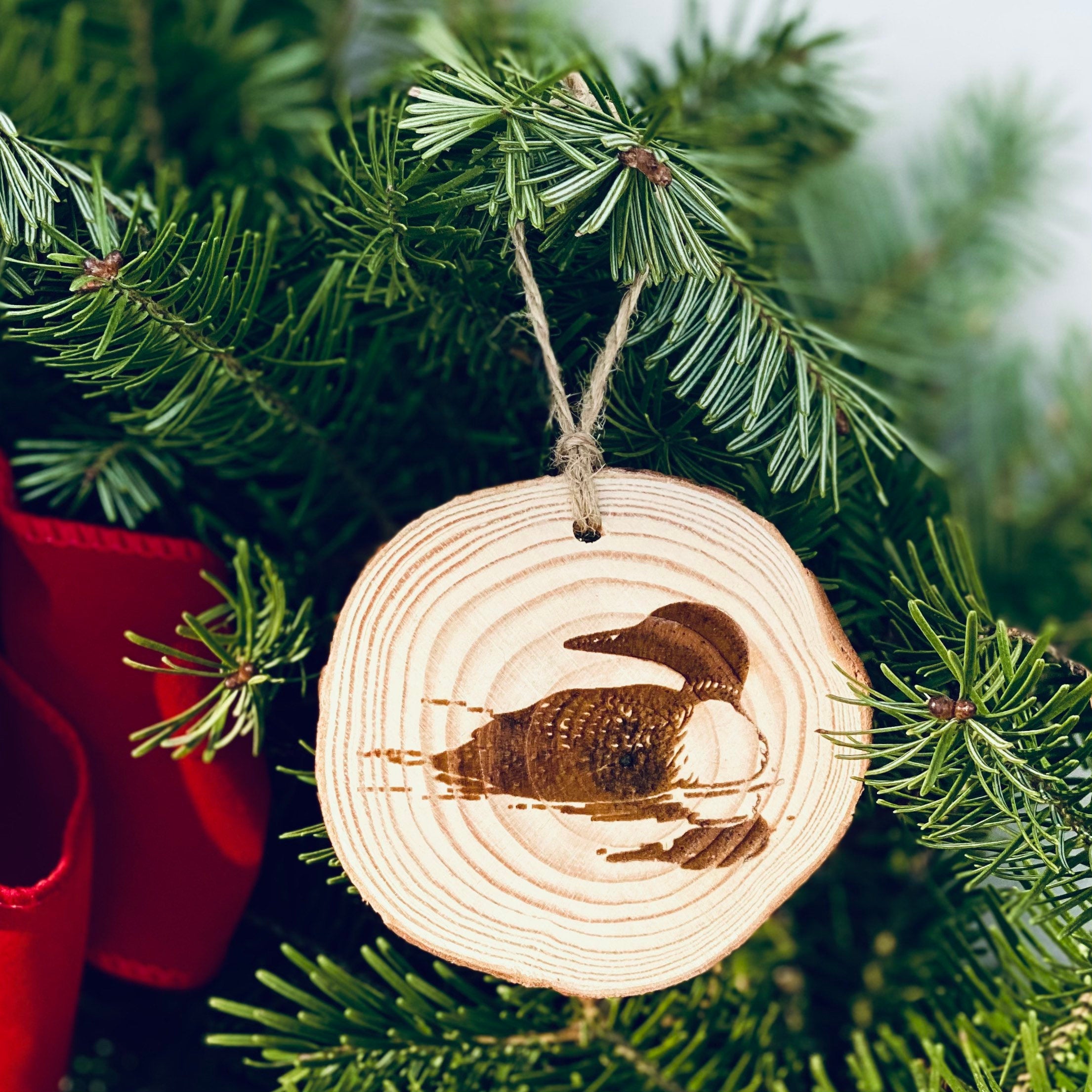 Loon Engraved Wood Christmas Ornament featuring a rustic pine wood slice with a detailed loon illustration.