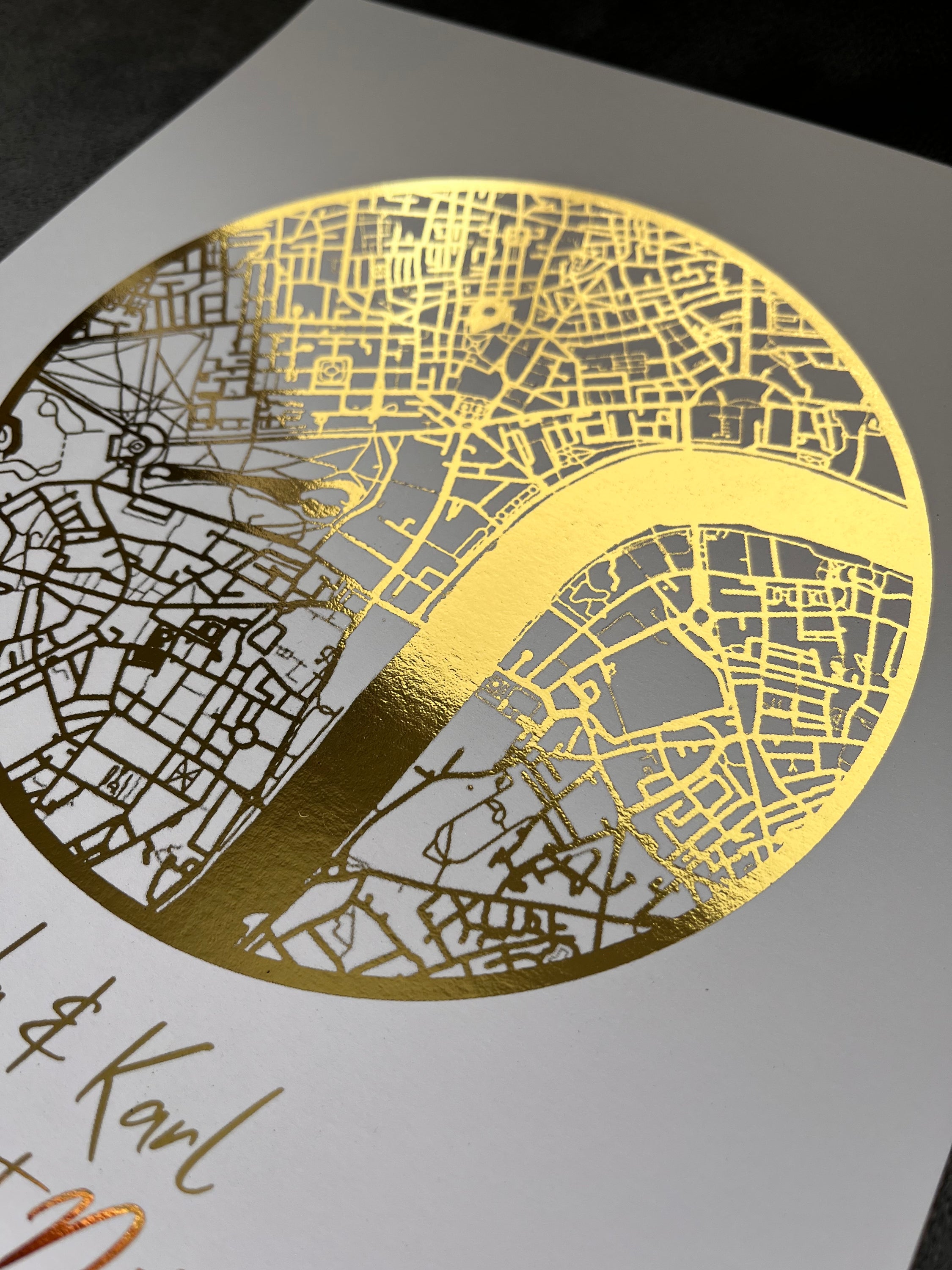 A beautifully crafted gold foil printed map in a circle shape, personalized with names and a location, symbolizing a couple's first date.