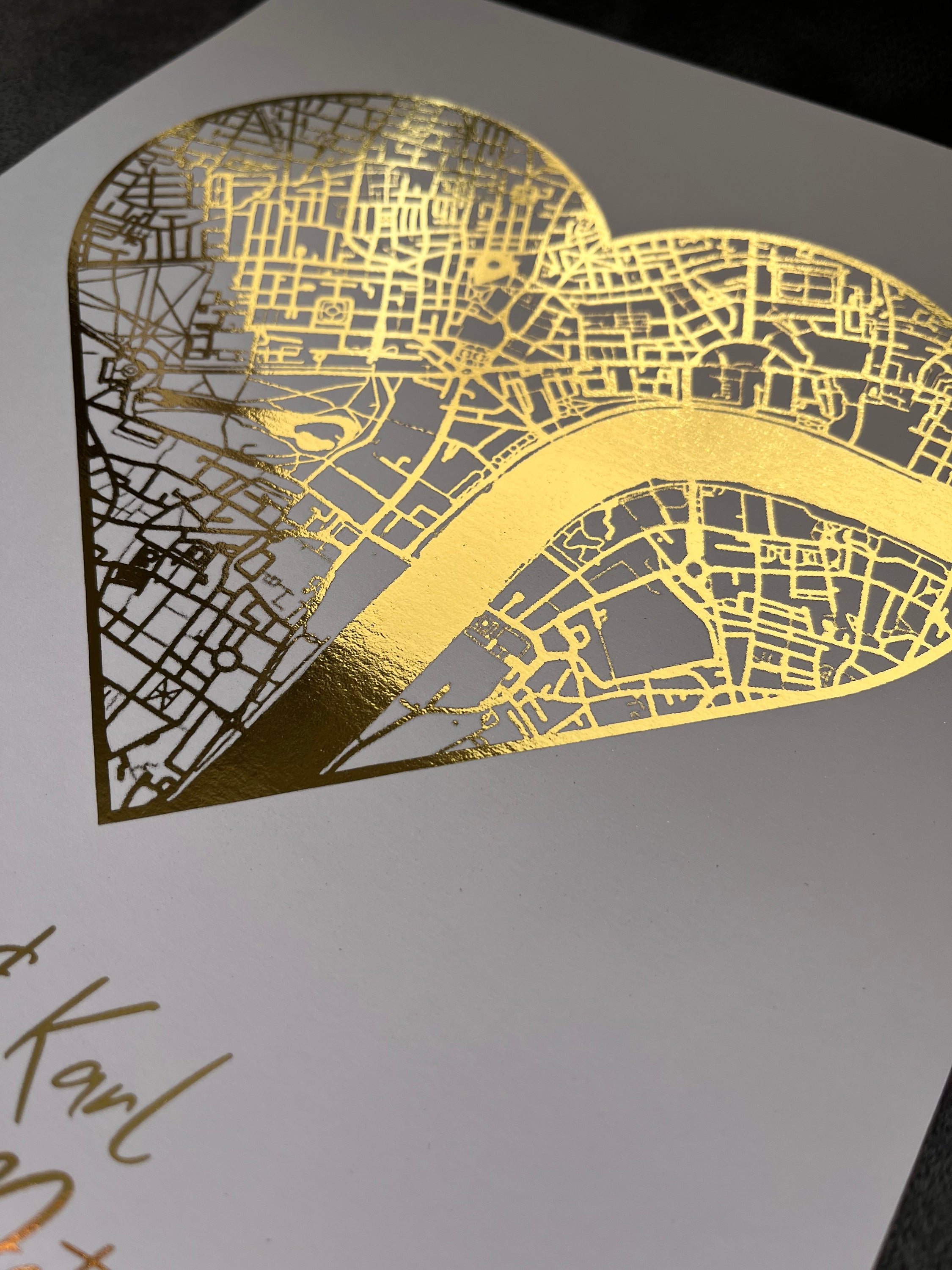 A beautifully crafted heart-shaped map featuring gold foil printing, personalized with couple's names and first date location.