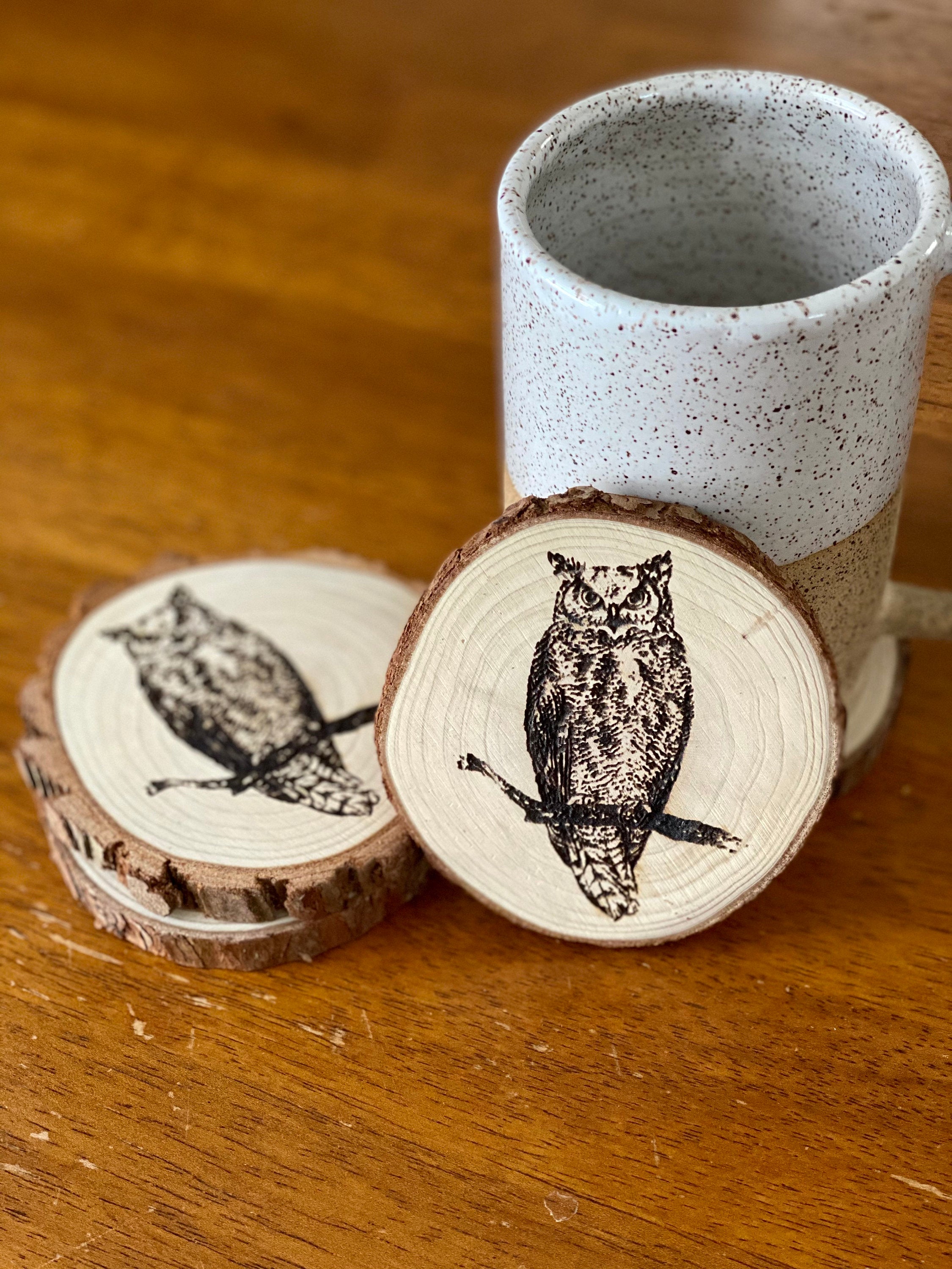 A set of four laser engraved wood coasters featuring intricate owl designs, showcasing their natural wood finish and unique craftsmanship.