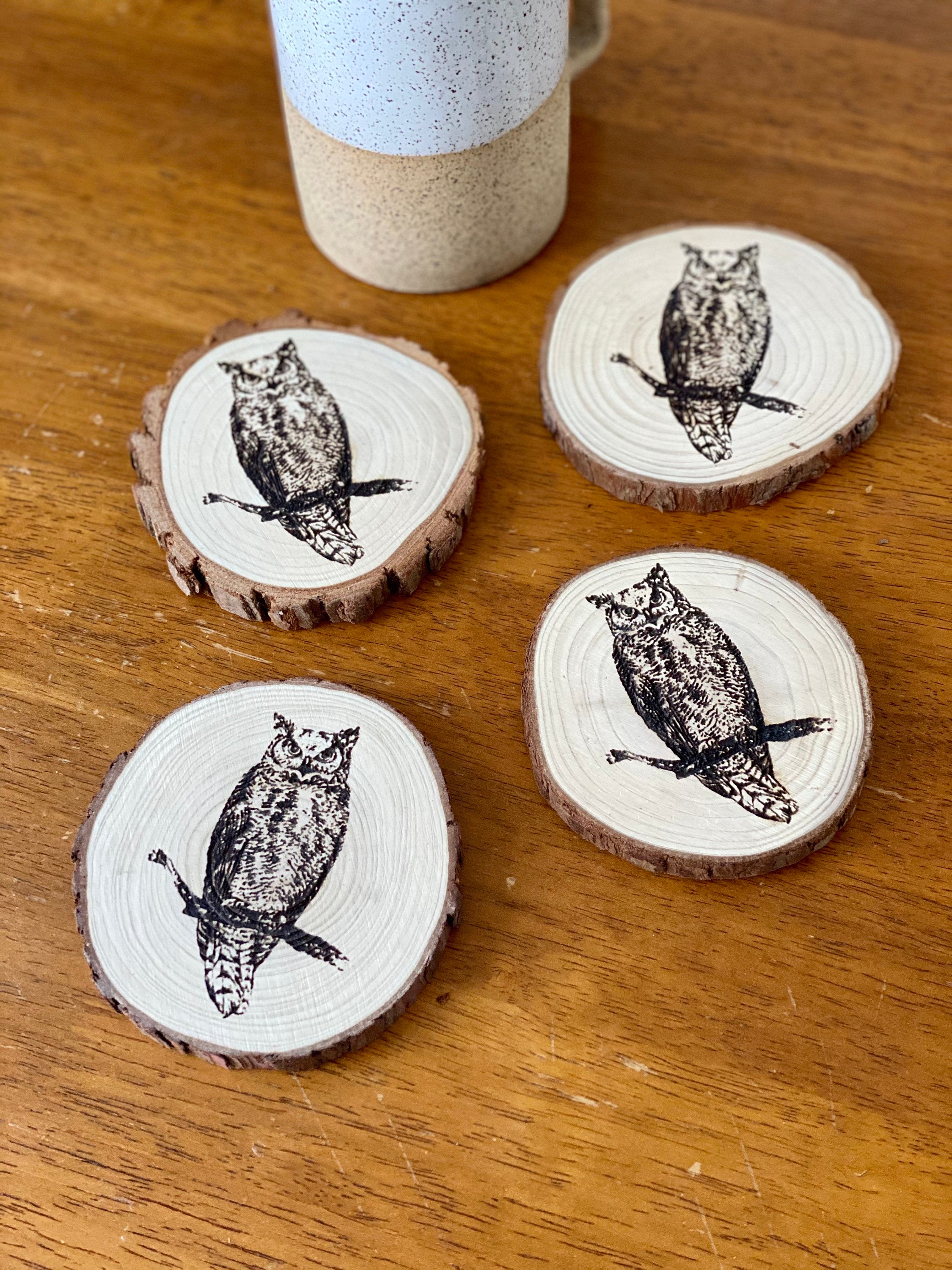 A set of four laser engraved wood coasters featuring intricate owl designs, showcasing their natural wood finish and unique craftsmanship.