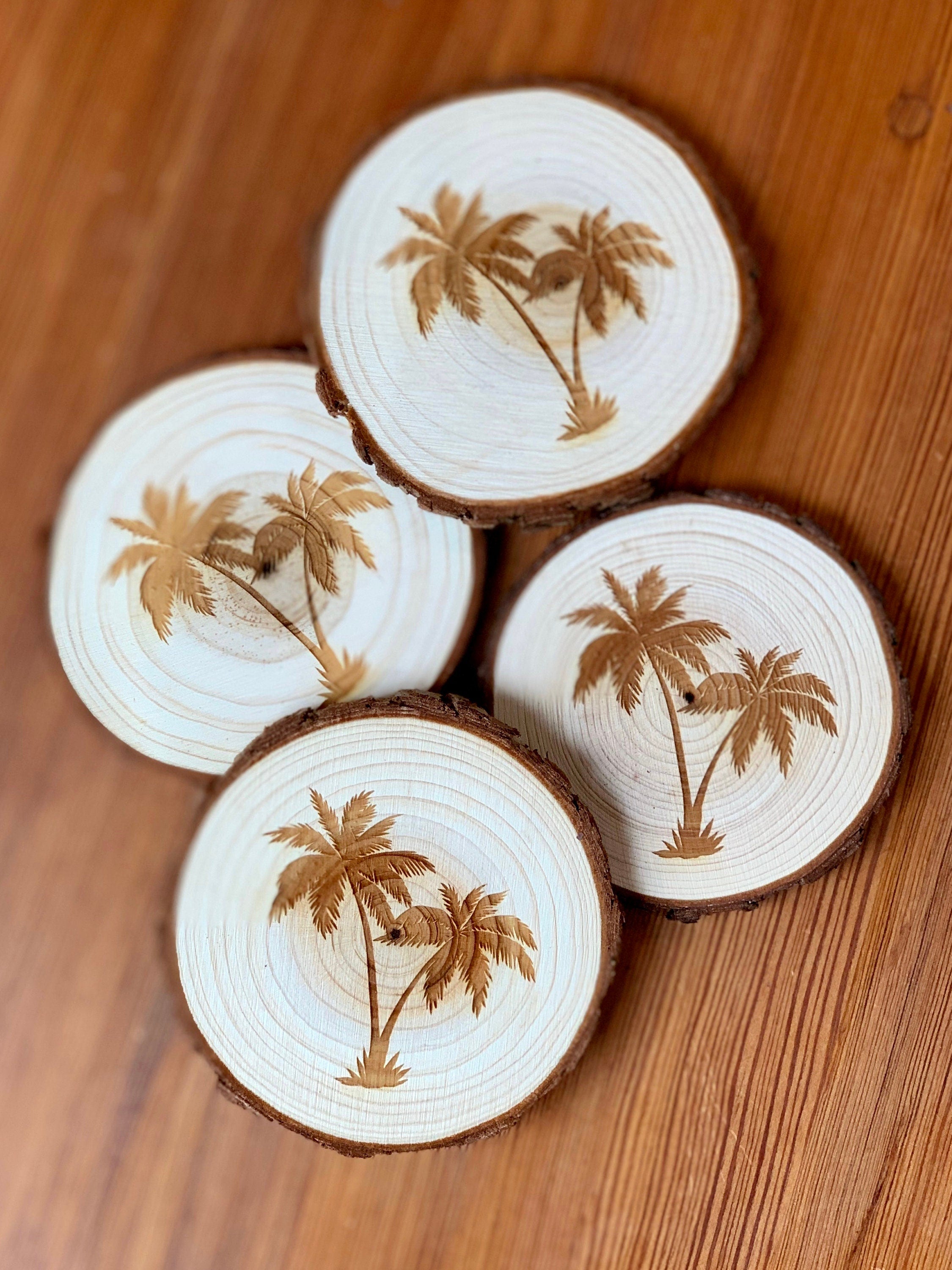 A set of four palm tree engraved wood coasters on a rustic wooden table, showcasing their natural finish and intricate designs.