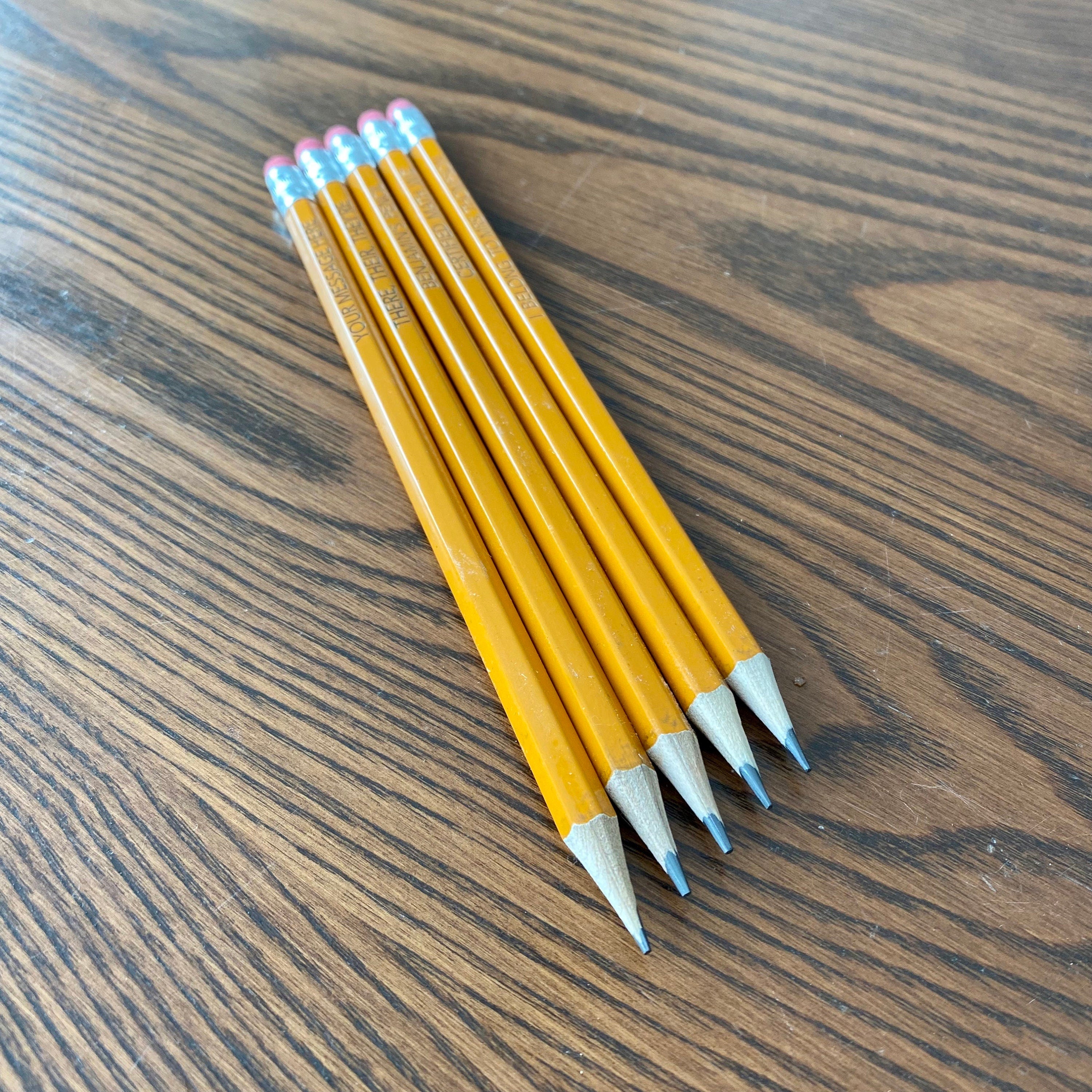 A set of personalized #2 pencils with laser engraving, showcasing custom messages and names.