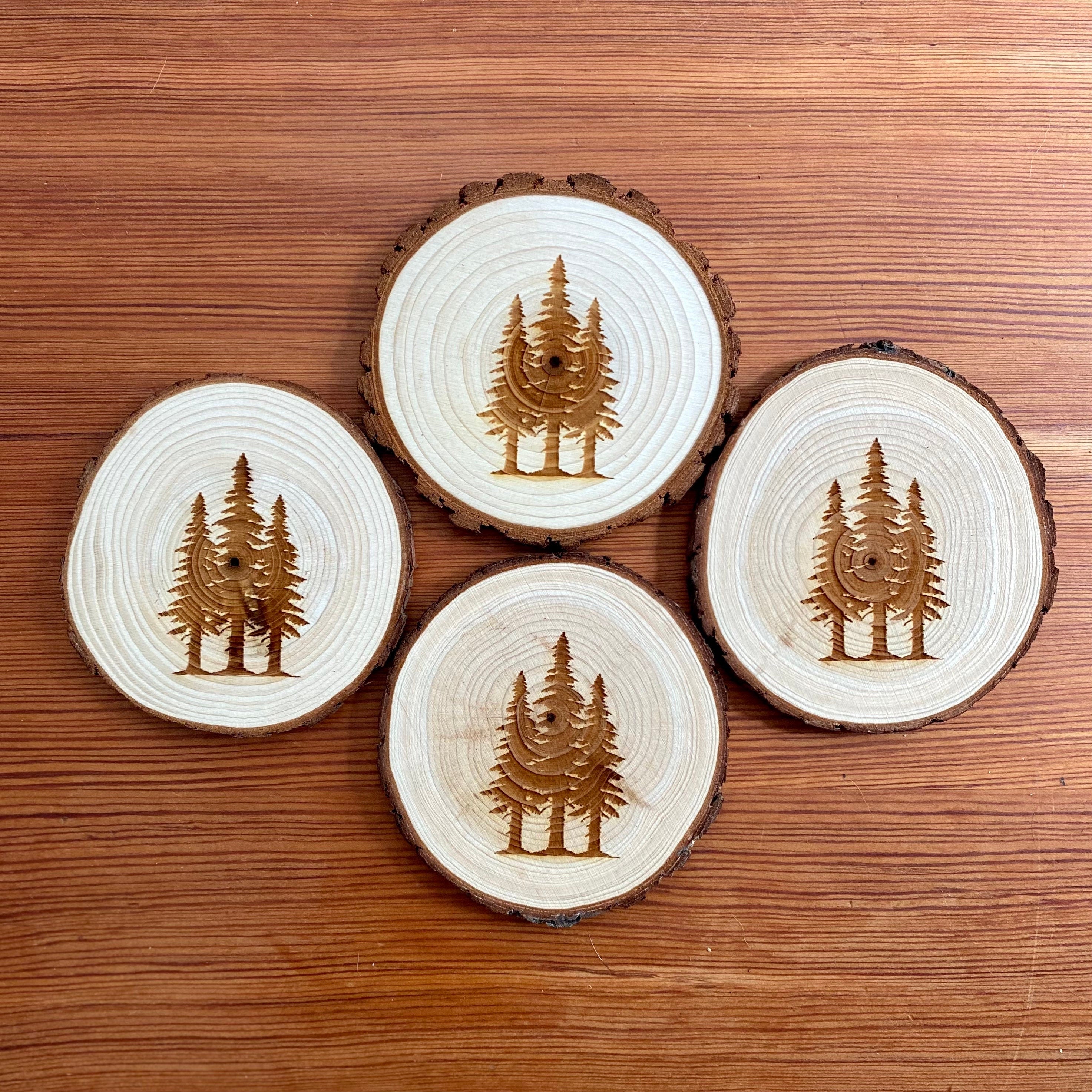 A set of four pine tree engraved wood coasters, showcasing intricate designs on a rustic wood surface, ideal for home decor.