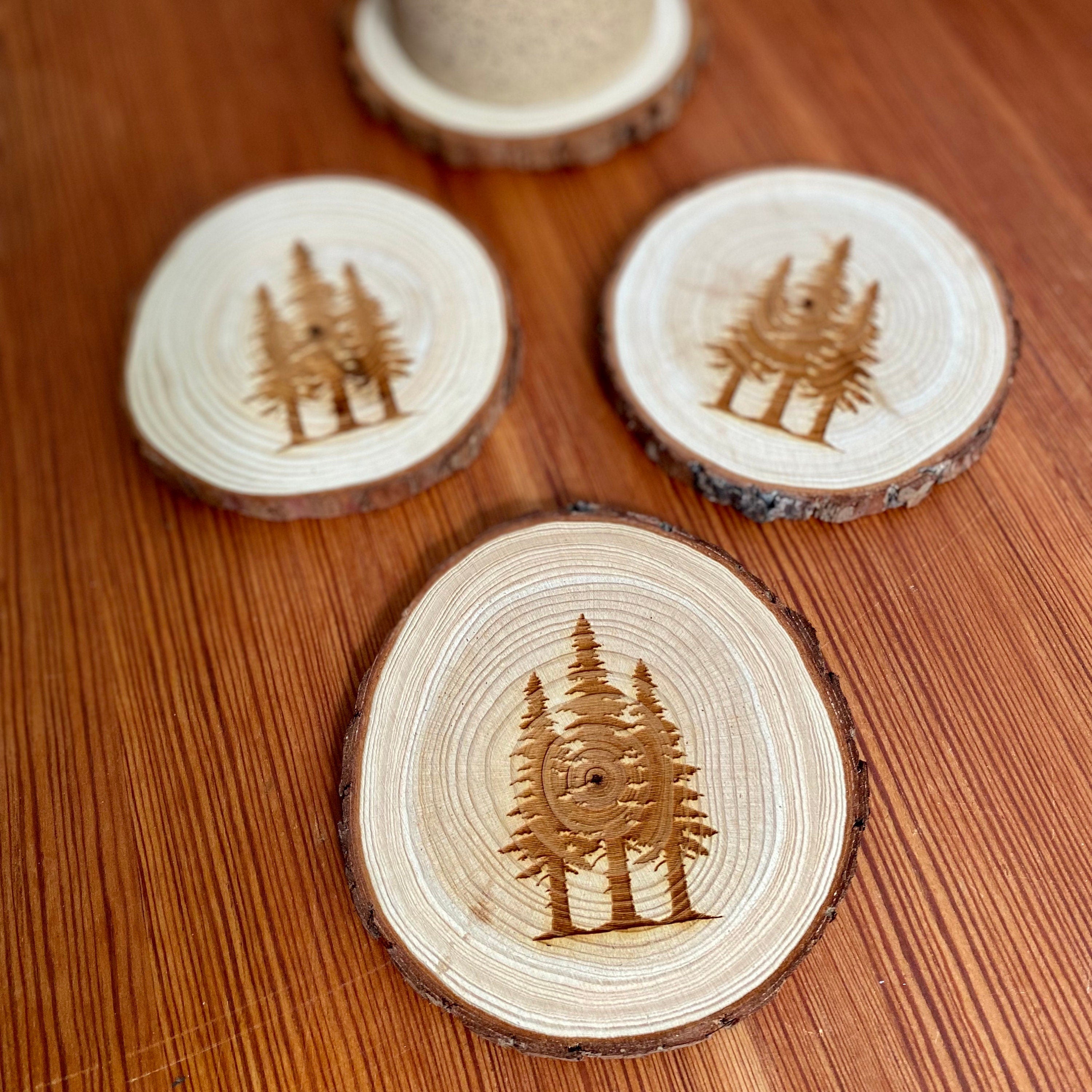 A set of four pine tree engraved wood coasters, showcasing intricate designs on a rustic wood surface, ideal for home decor.